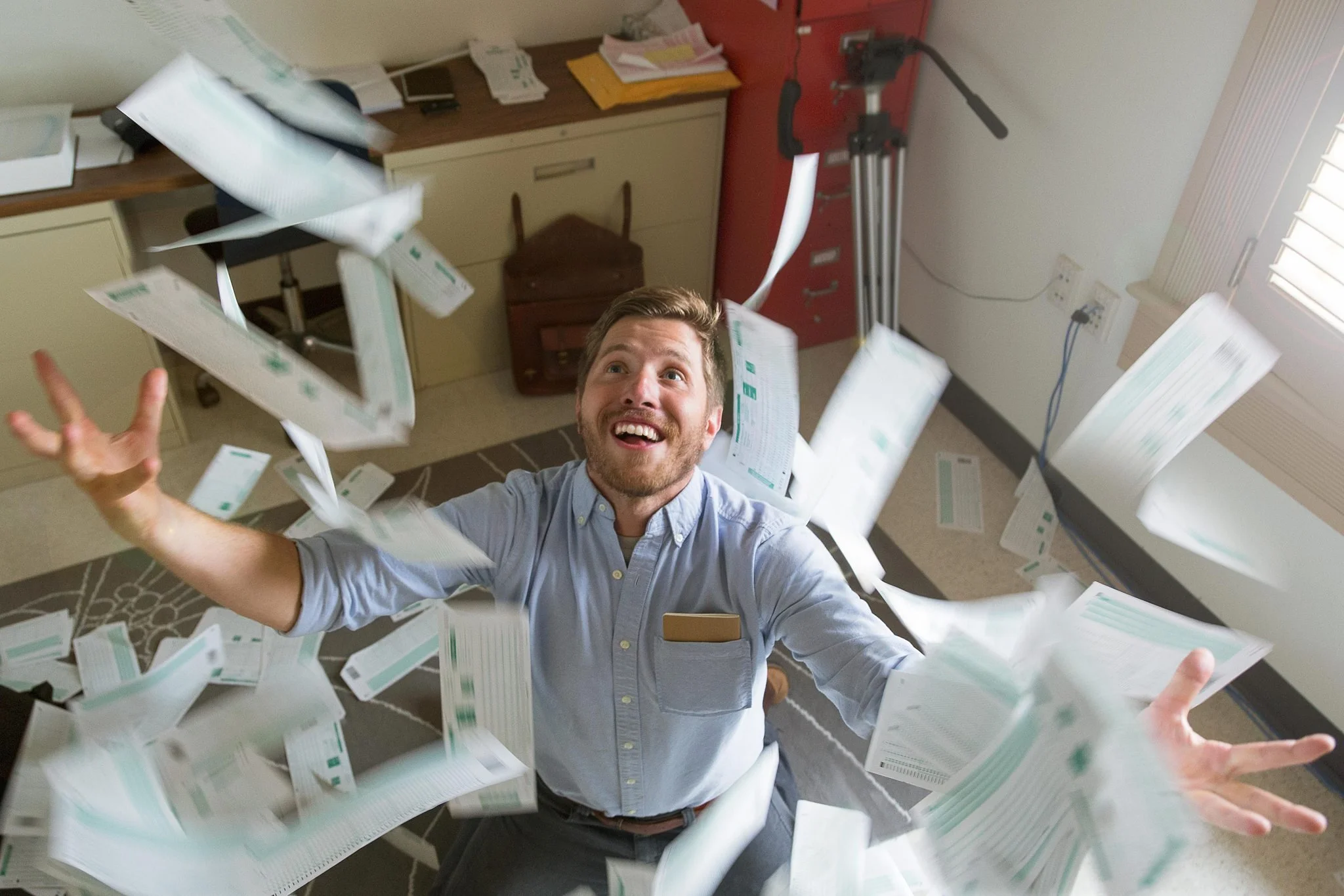 Creative branding portrait of a businessman joyfully throwing papers in the air during a photoshoot in San Antonio