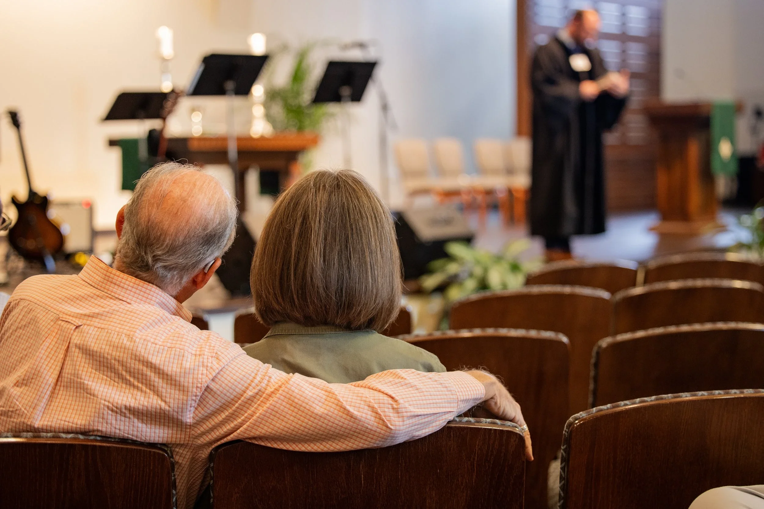 Couple seated together during a church worship service listening to a pastor speak from the stage