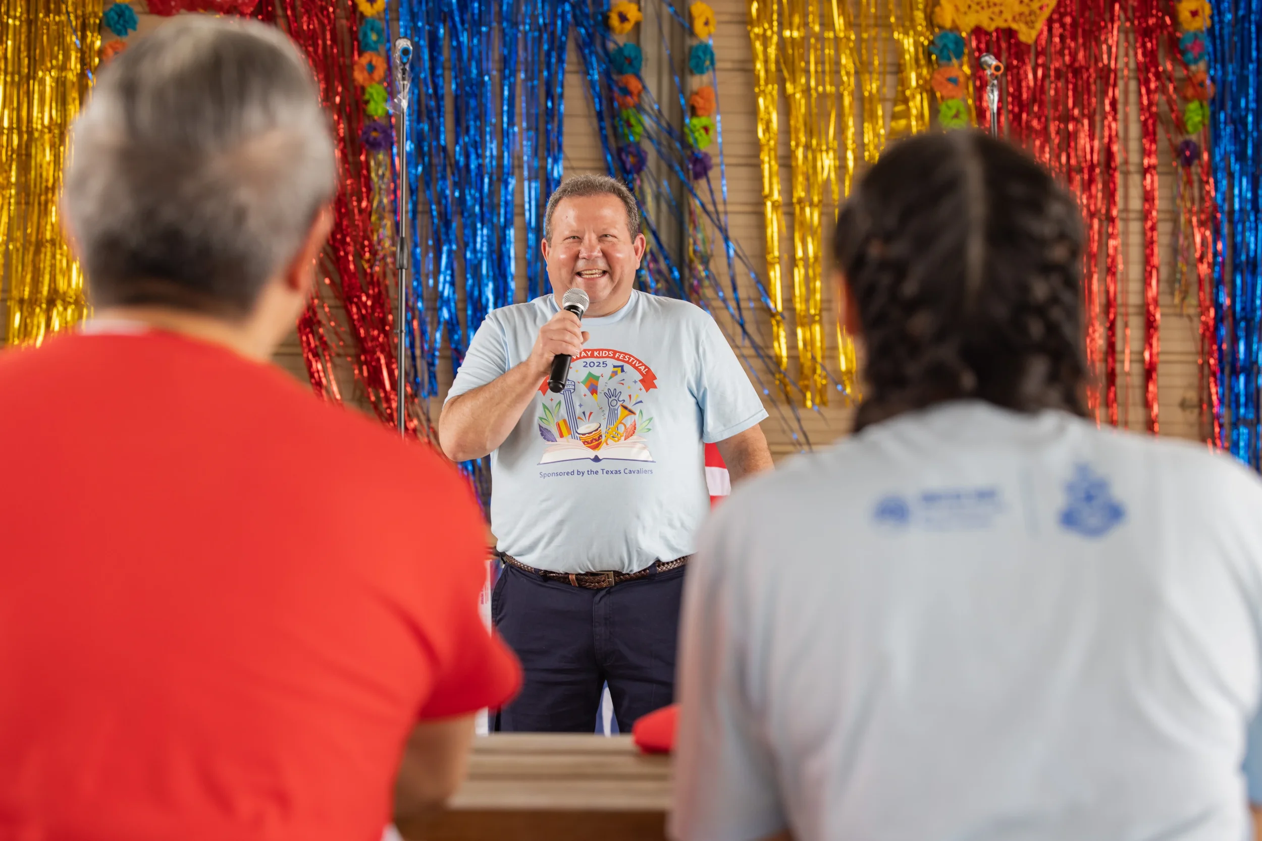 Event emcee speaking on stage with microphone during United Way Kids Fest celebration.