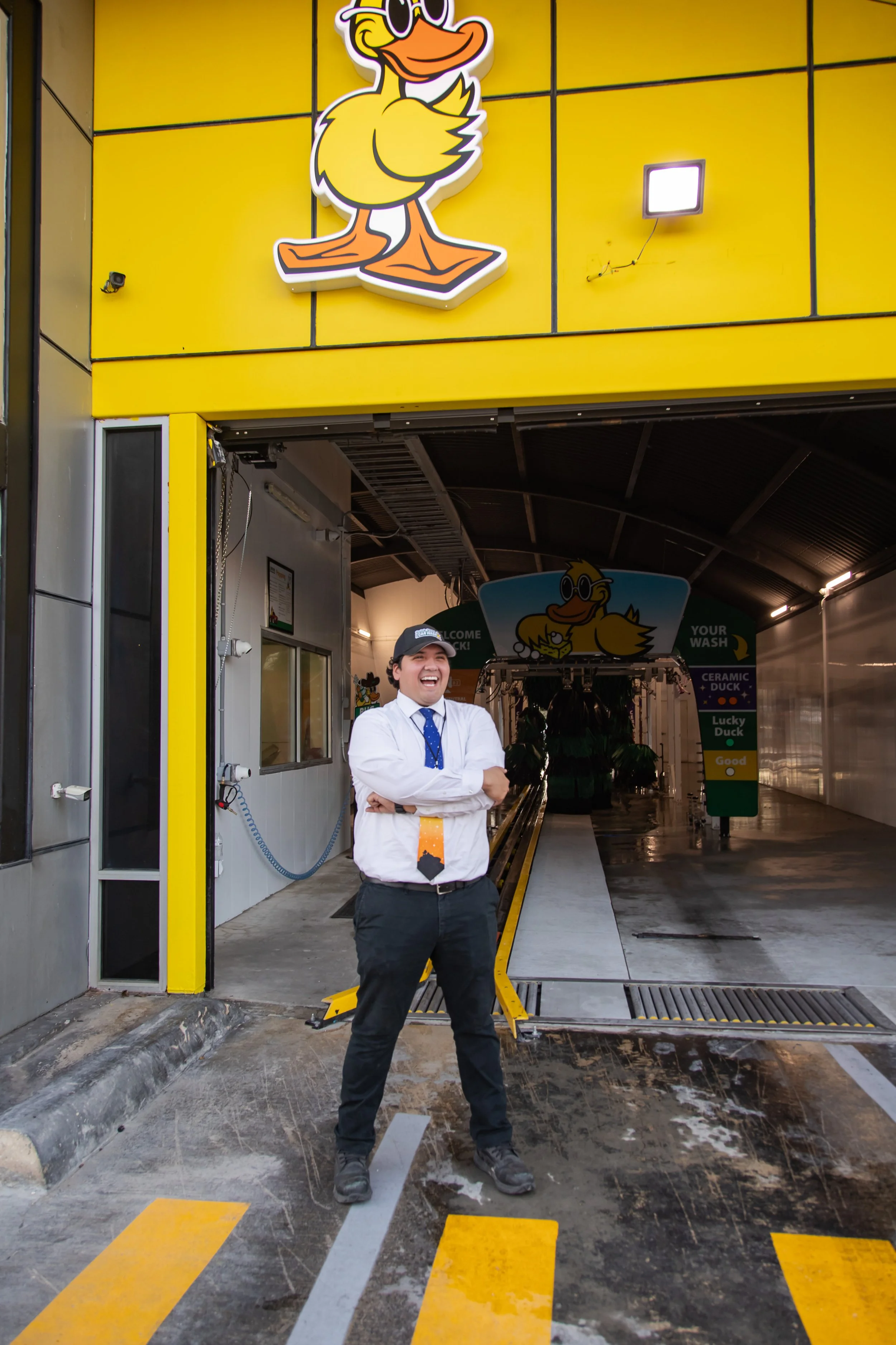 Quick Quack Car Wash team member standing confidently at car wash entrance in branded professional attire.