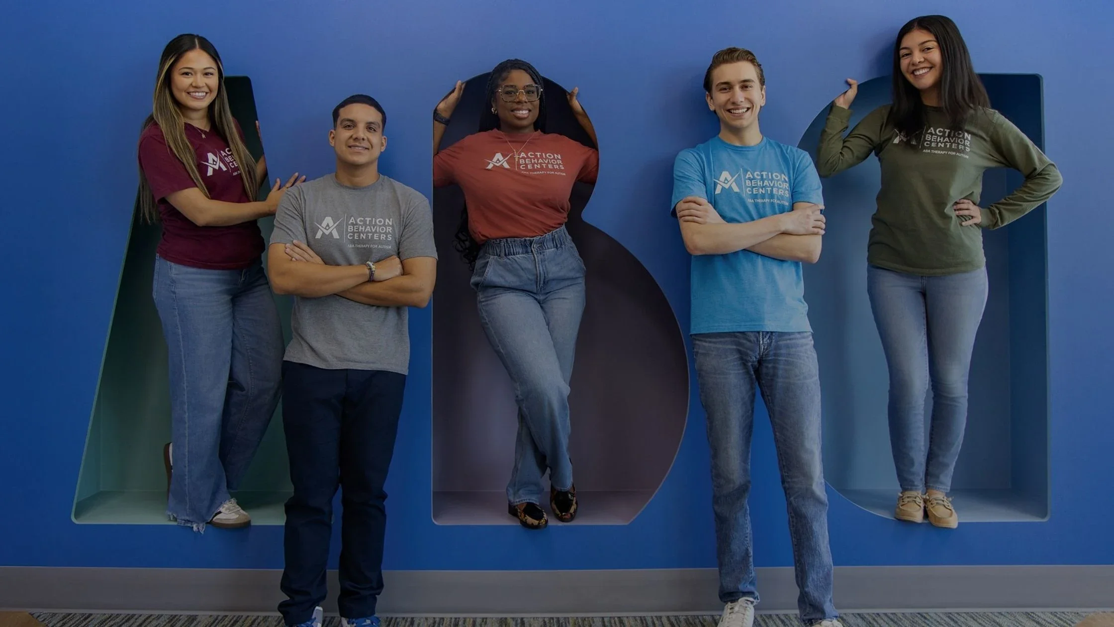 Action Behavior Centers staff posing together in front of the colorful ABC wall at the Potranco location