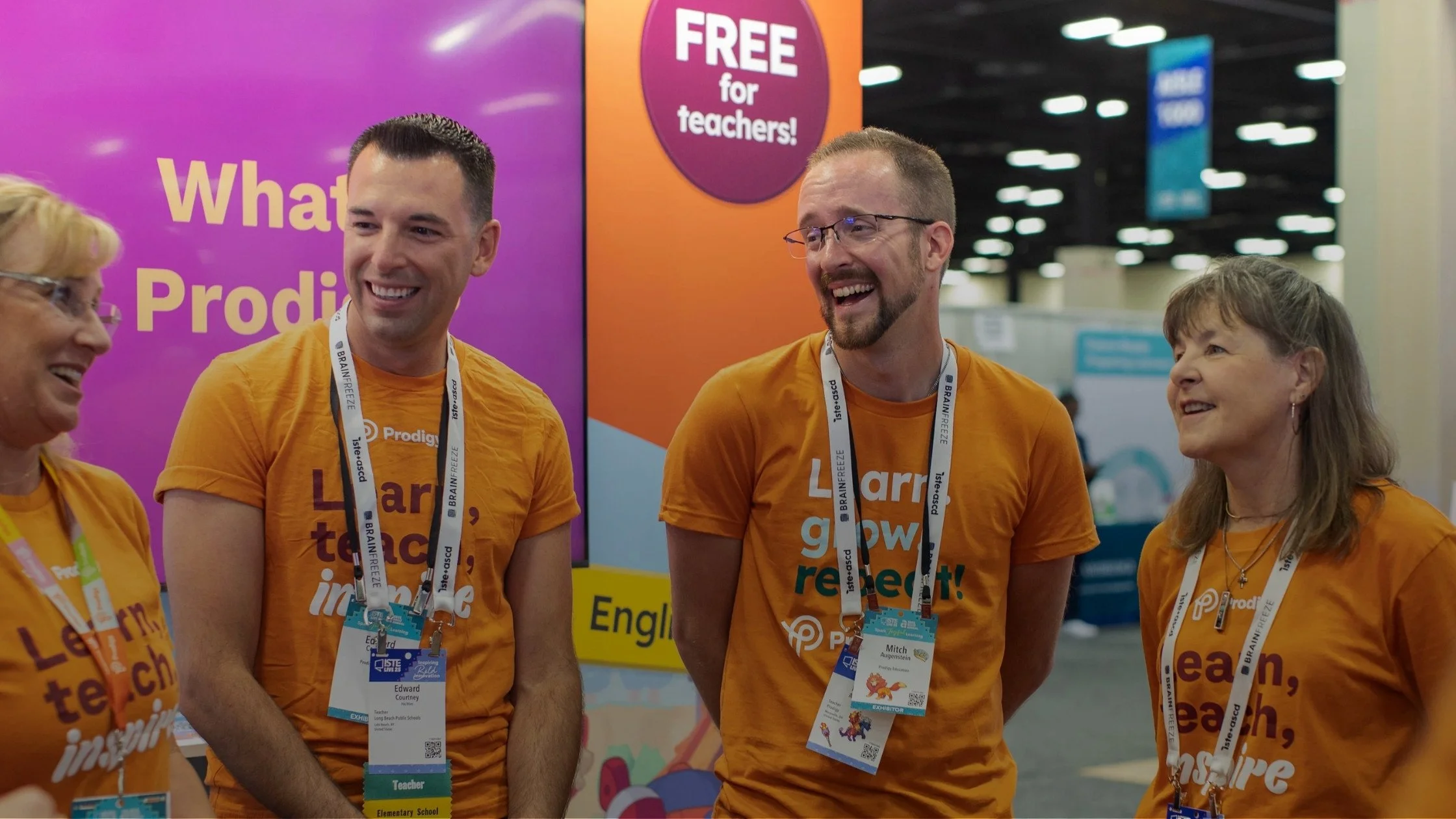 Prodigy team members in branded orange shirts laughing together at the ISTE education technology conference booth.