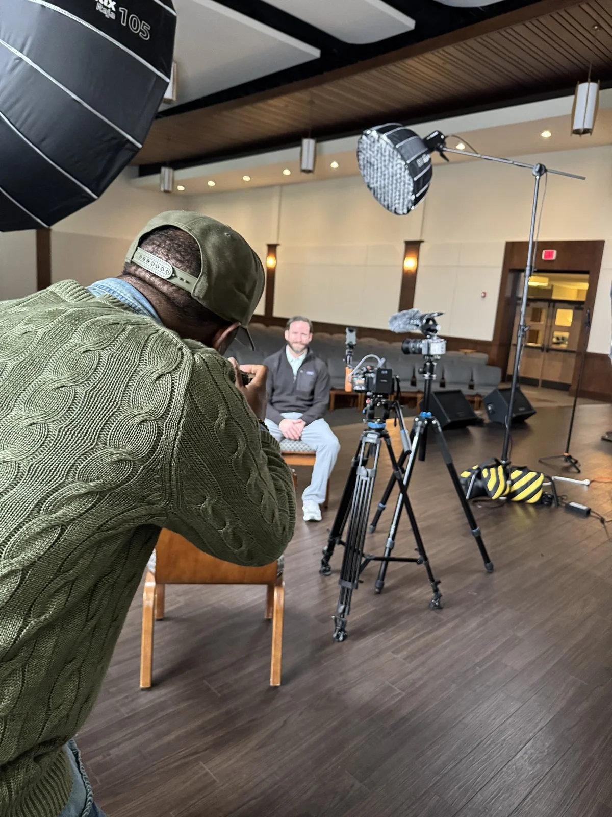 Behind the scenes of a corporate video and photoshoot setup in San Antonio, showing photographer and lighting equipment focused on a seated professional
