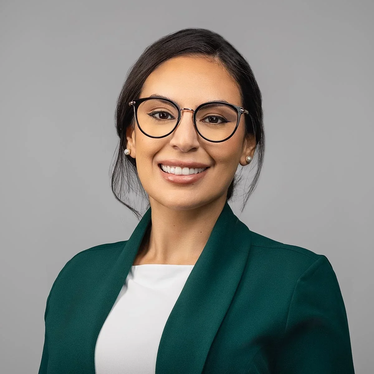 Professional headshot of a female medical professional in a white coat with a confident smile, photographed in San Antonio.