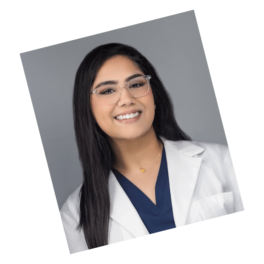 Professional headshot of a female doctor wearing a white coat and glasses, smiling against a gray background.