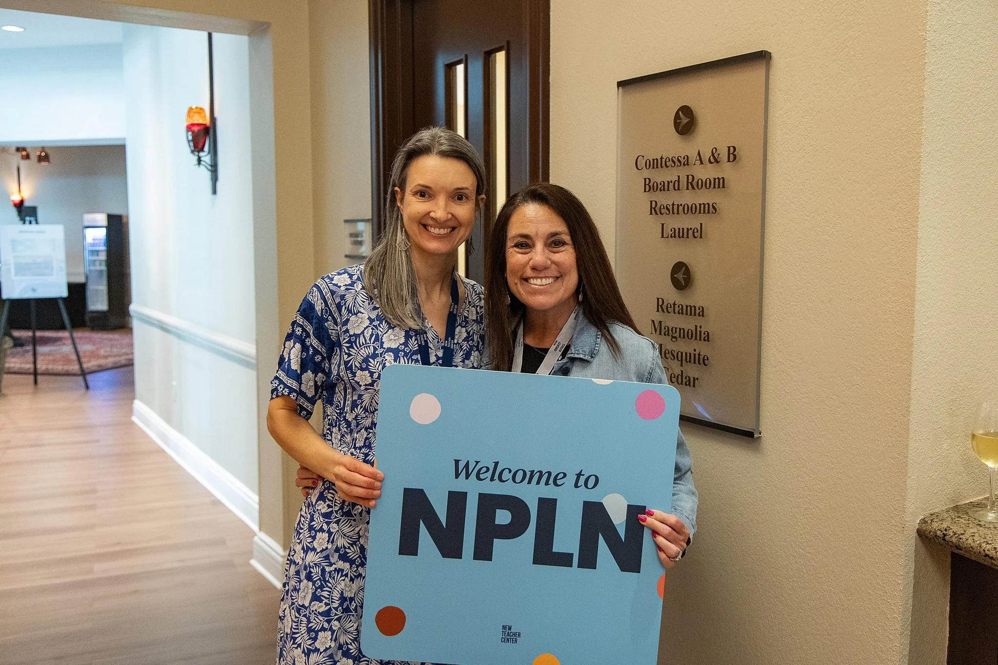 Two attendees pose with a Welcome to NPLN sign at the New Teacher Center conference.
