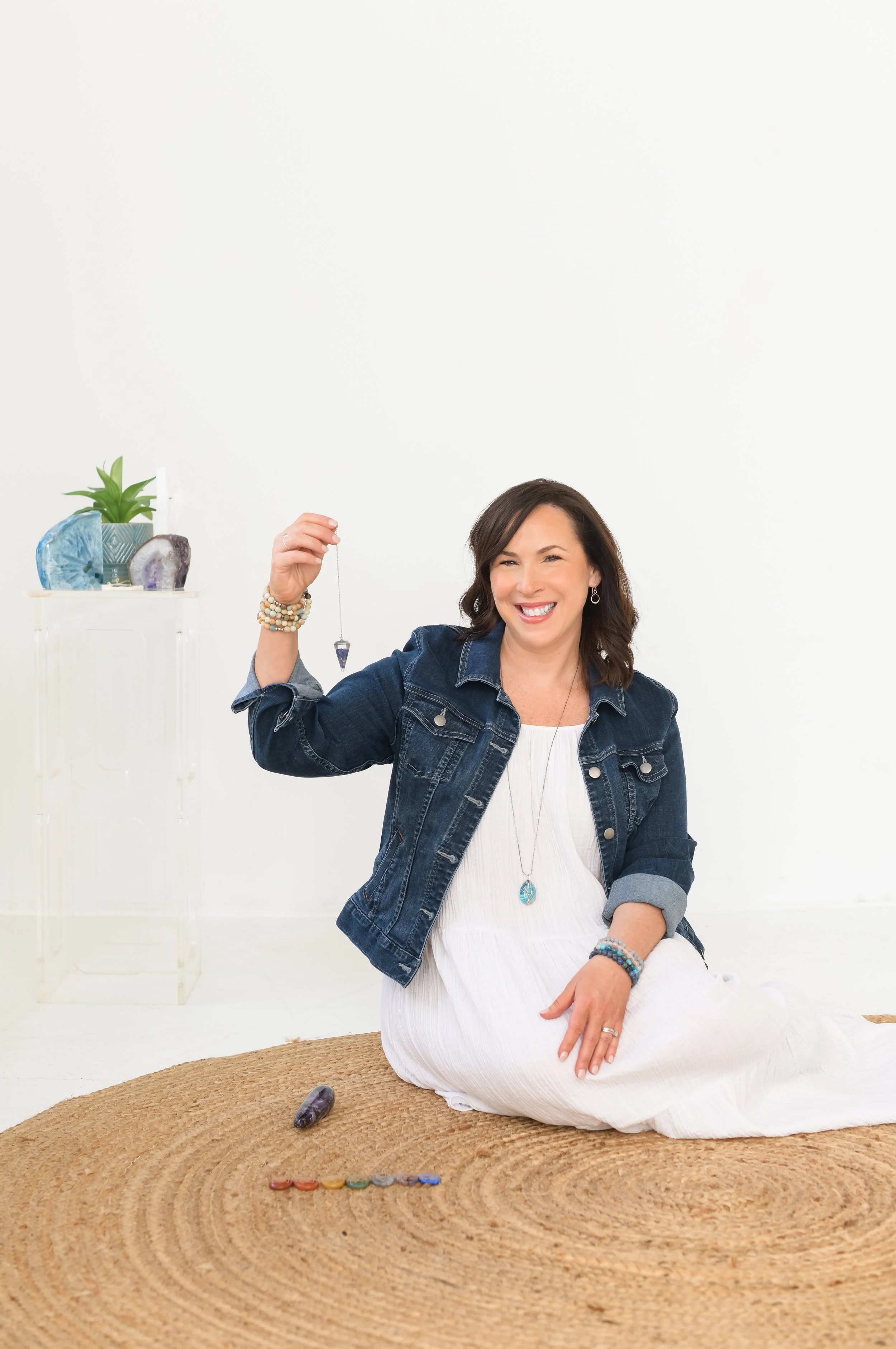 Jill Vetstein is sitting on the floor of her Natick MA office where she performs Reiki and energy healing. She's holding a dowsing pendulum.
