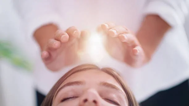Jill Vetstein is a Reiki Master and this image depicts a client laying on the table with hands above their first chakra and a light orb in between.