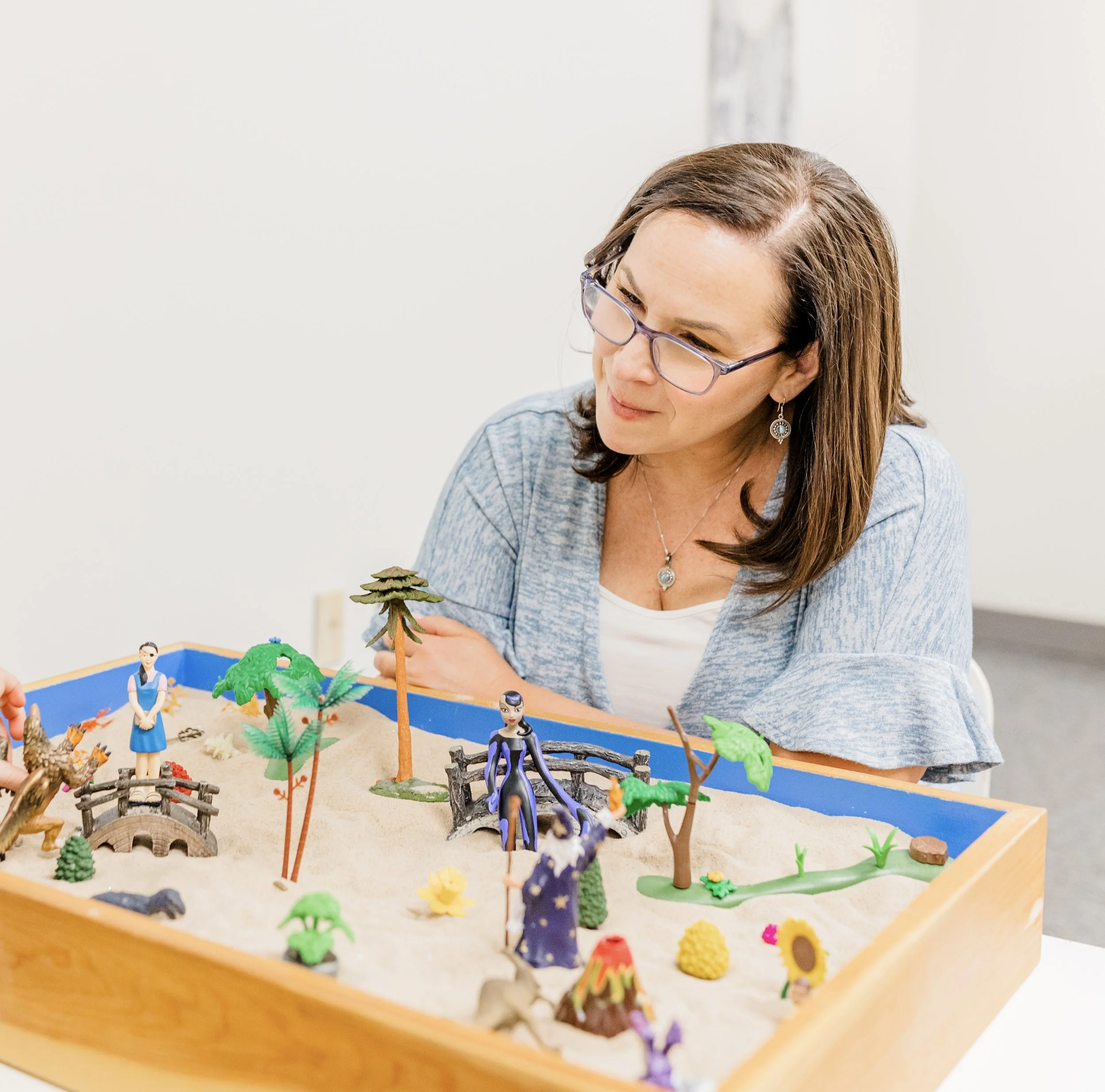 Jill is sitting in her Natick, MA office during a sand table session with a client seeking better emotional regulation