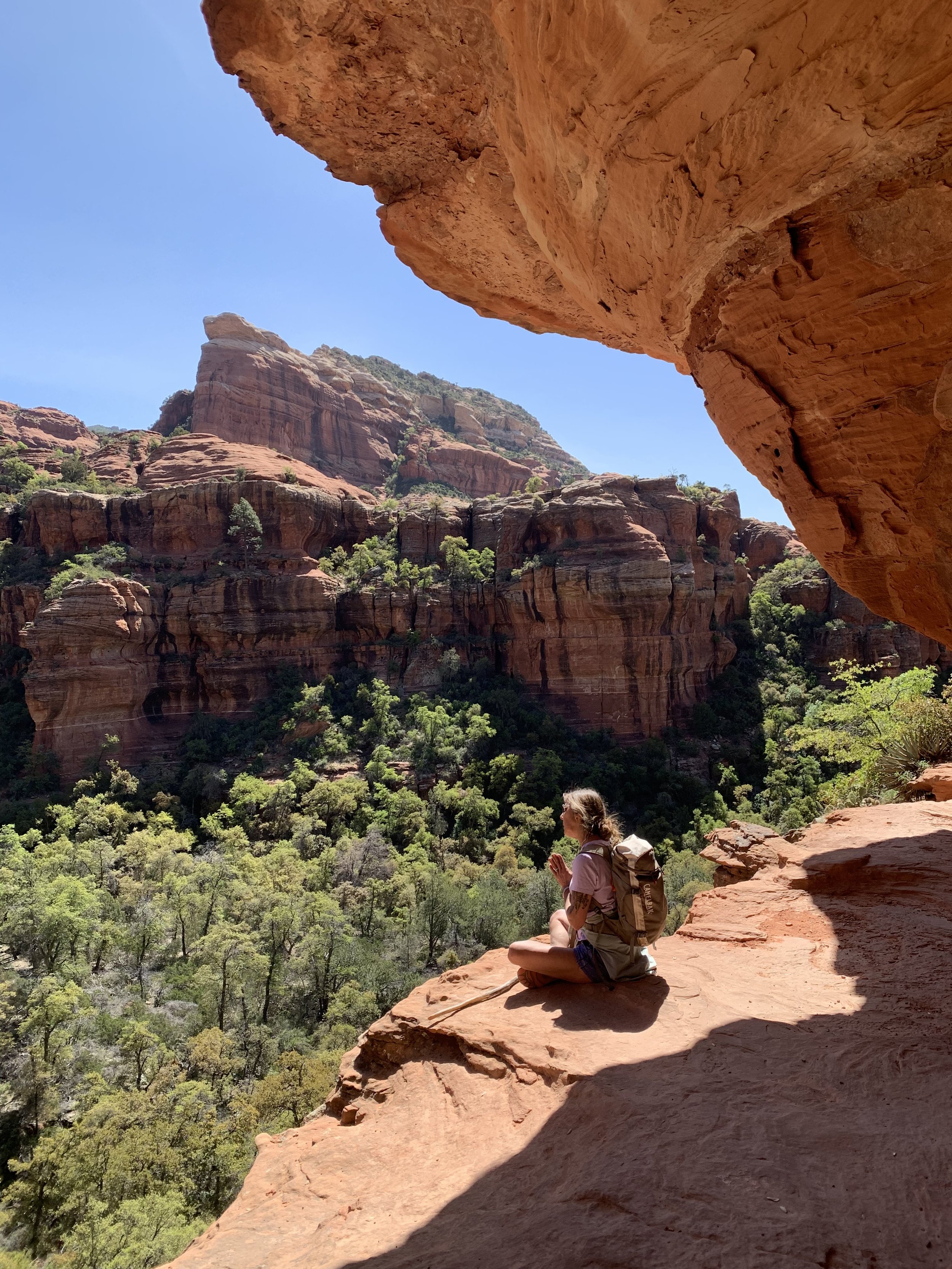 Woman sitting in a yoga position on a stump in the woods.