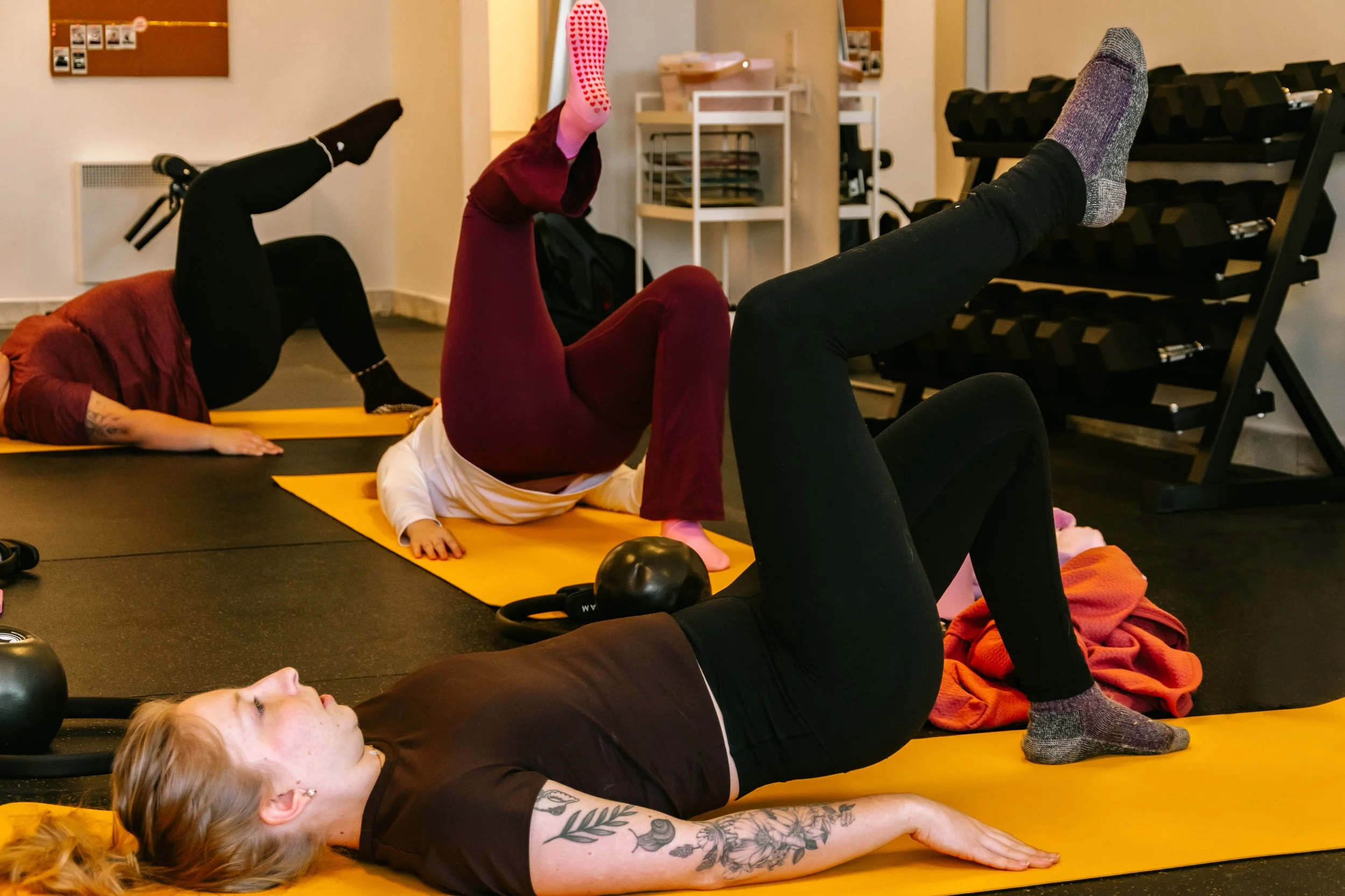 Groupe de personnes faisant une séance de pilates sur des tapis jaunes dans une salle intérieure.