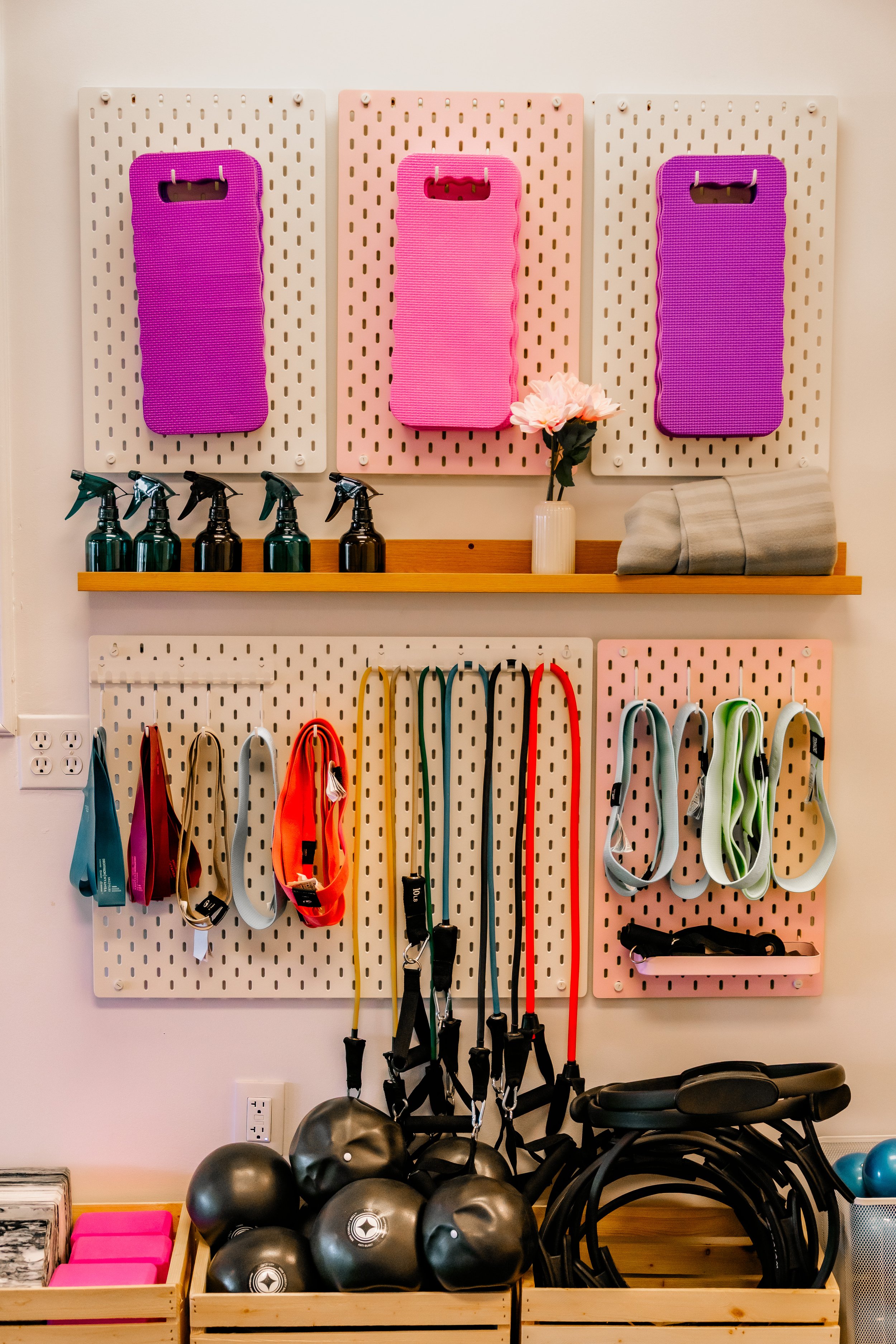 Organisateur de matériel de sport avec balles, bandes de résistance, sprays, serviettes, sacs de course et appareils de fitness dans une salle de sport.