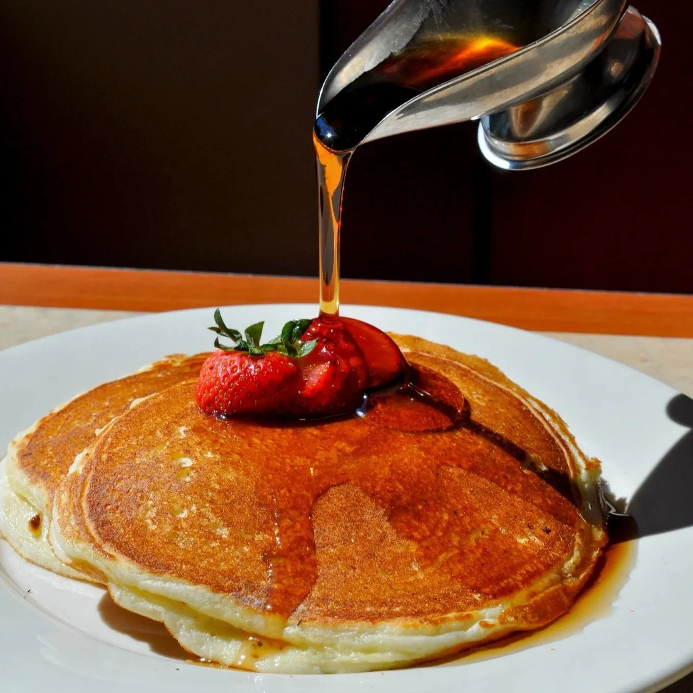 Stack of fluffy pancakes with maple syrup dripping down the side, food photography for a Sarasota, FL breakfast restaurant