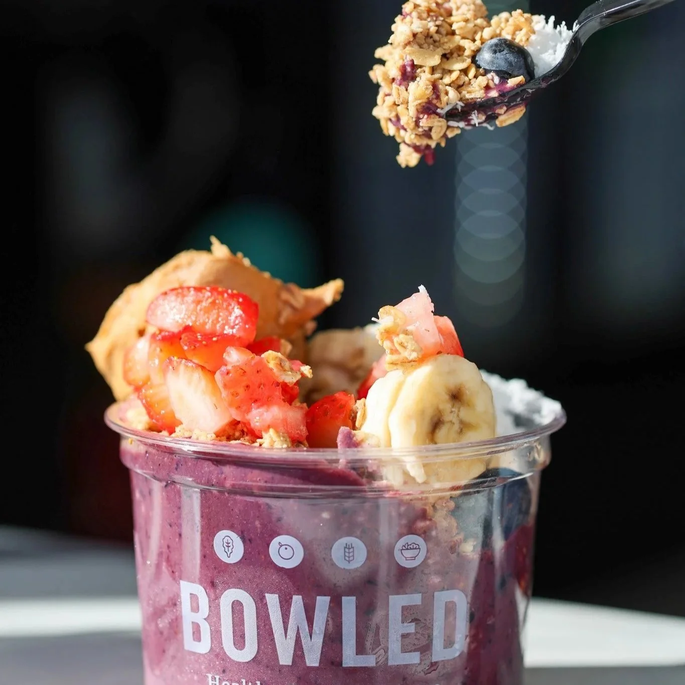 Spoon scooping into a creamy açaí bowl topped with strawberries, banana and granola, food photography for a Destin, FL restaurant
