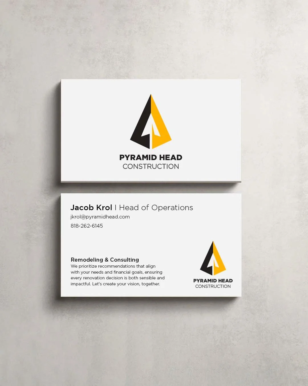 Business card for Pyramid Head Construction, featuring a yellow and black triangle logo, company name, and contact information for Jacob Krol, Head of Operations. Includes email, phone number, and a brief description of services focused on remodeling and consulting.