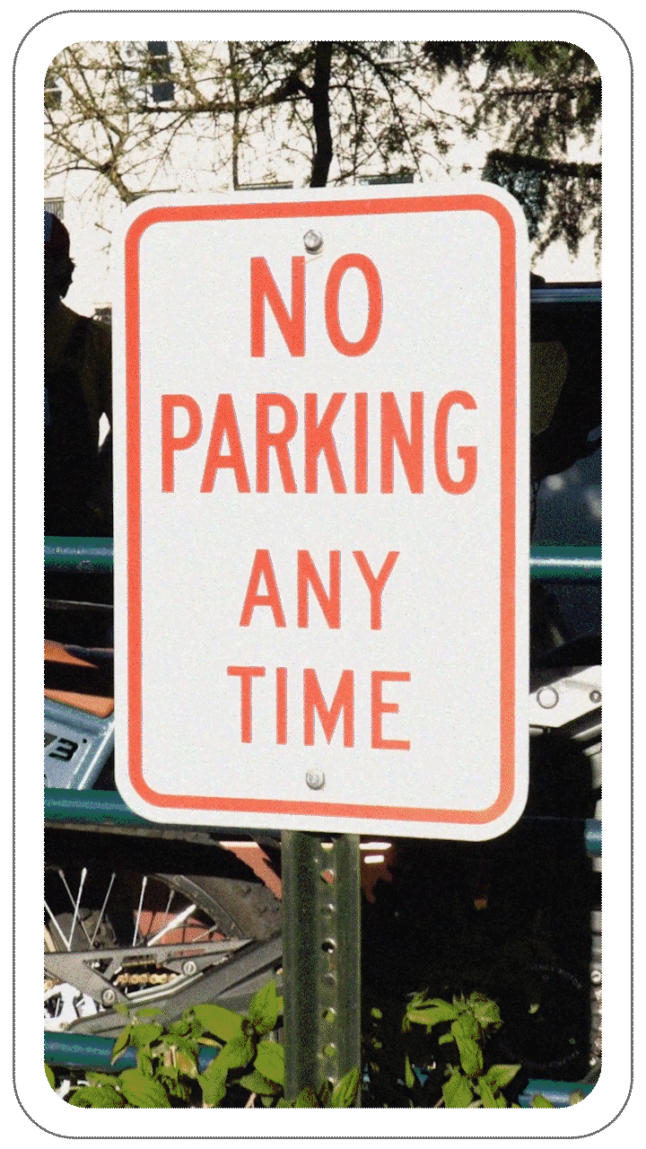"No Parking Any Time" sign with red text on a white background, mounted on a green metal pole.