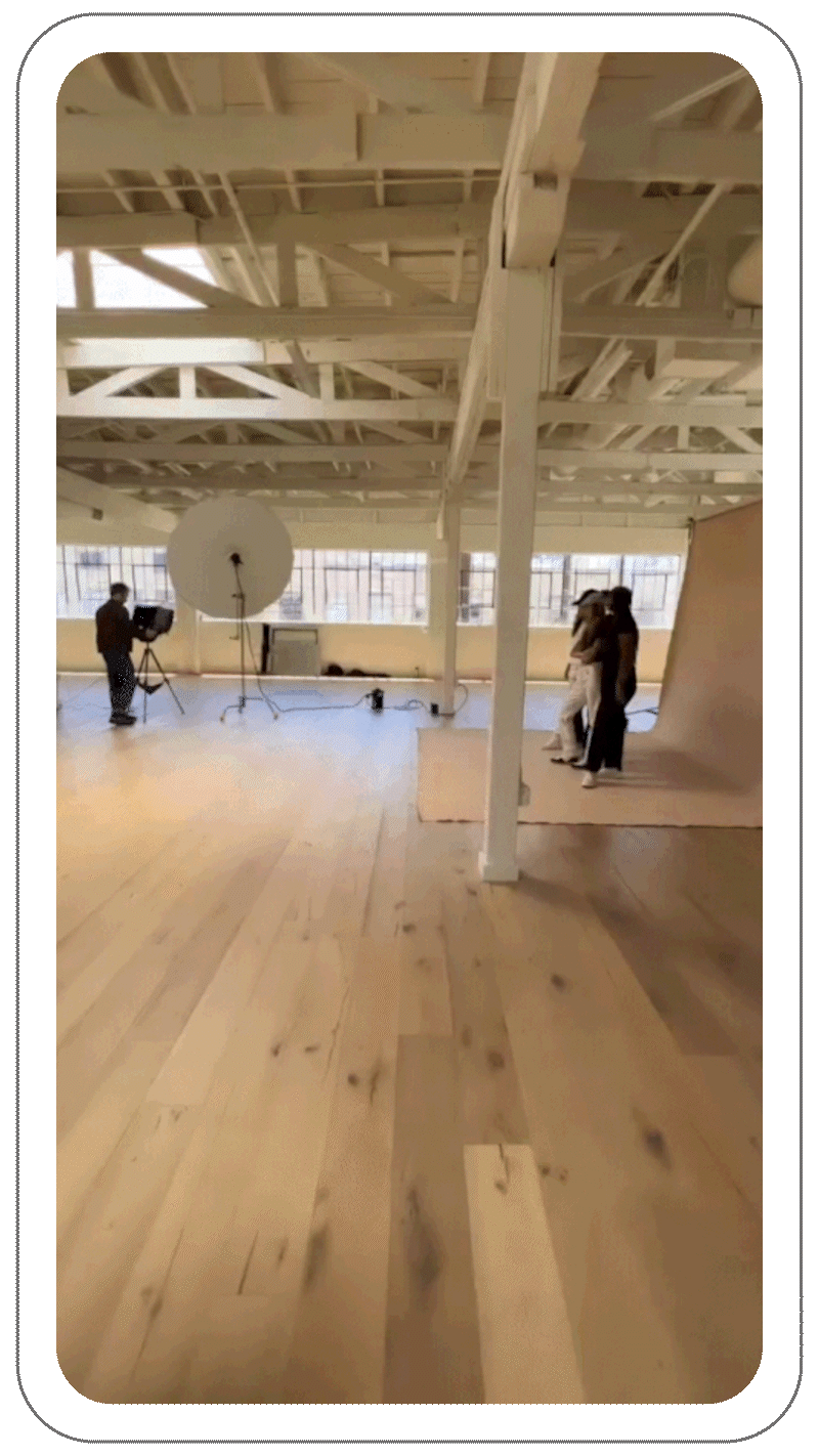 Photo studio with a photographer, lighting equipment, and two people posing in front of a backdrop.