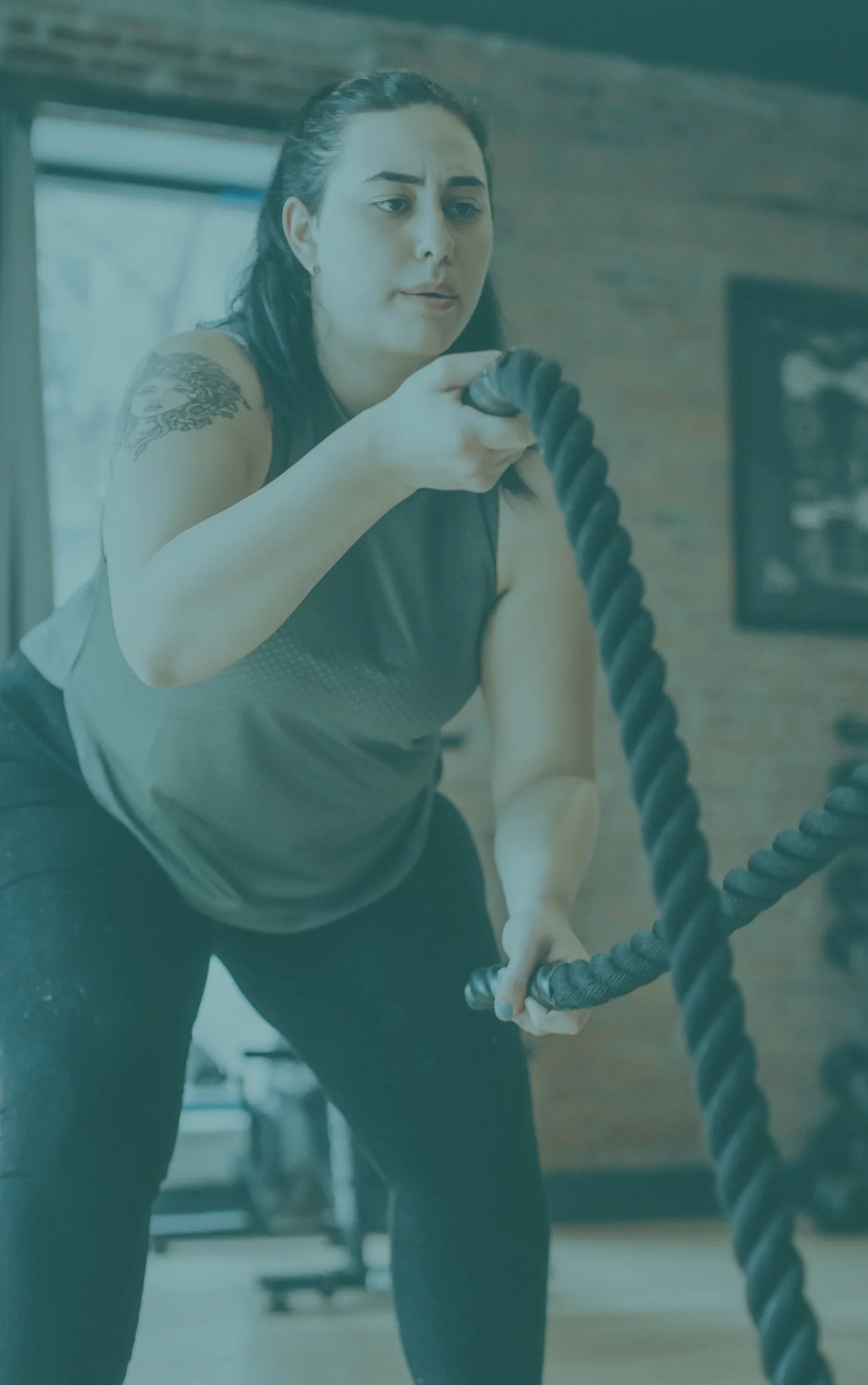 Person exercising with battle ropes in a gym setting.