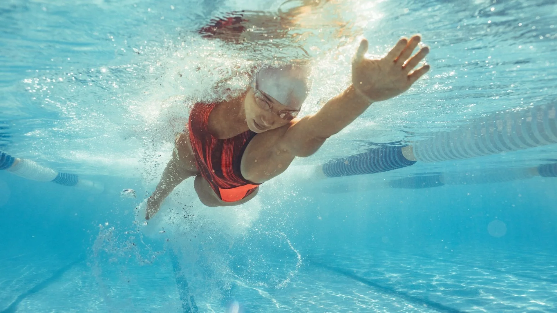 Underwater view of a female athlete swimming freestyle in a clear pool
