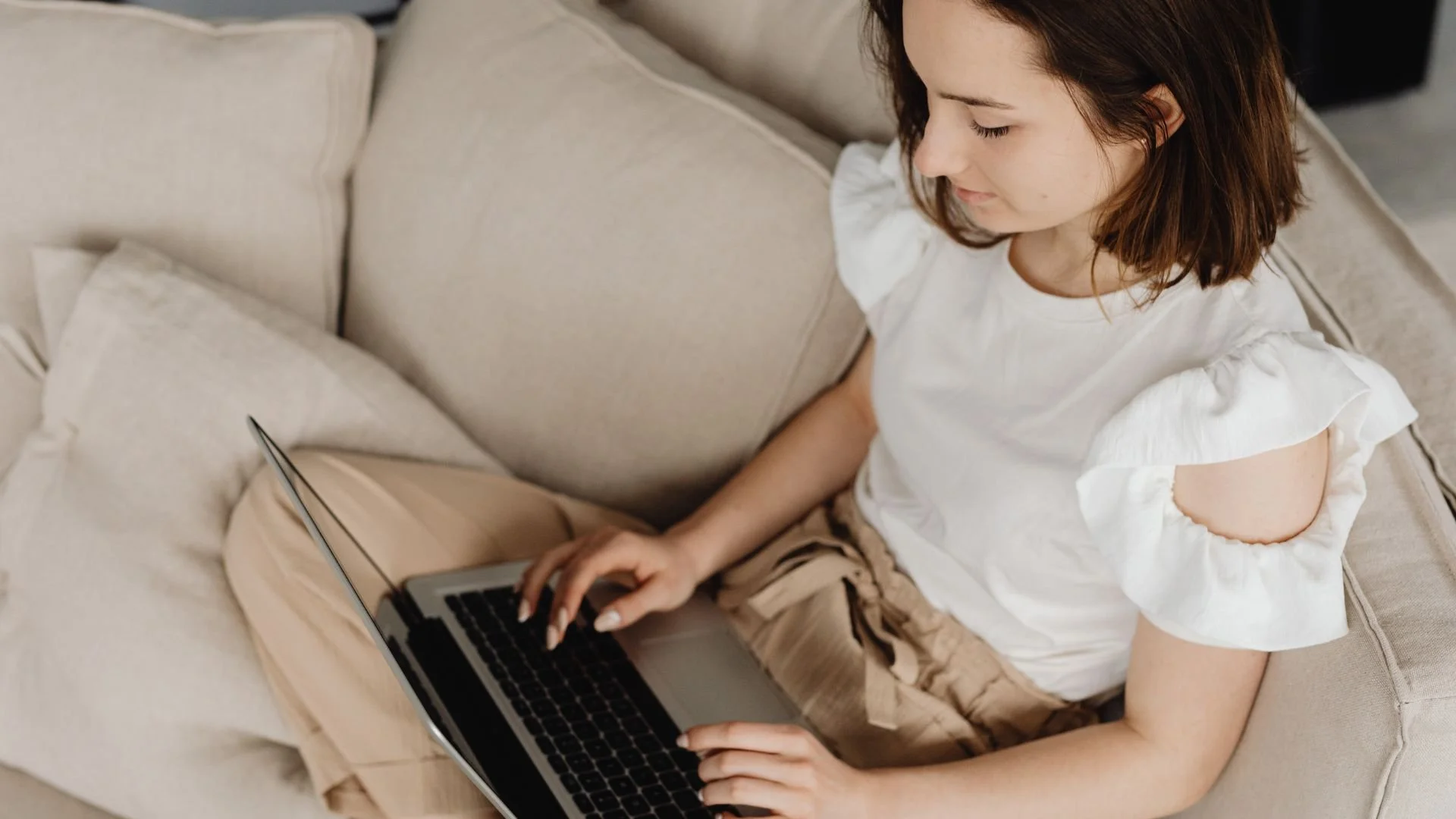 Woman sitting on a couch attending an online therapy session for depression on her laptop