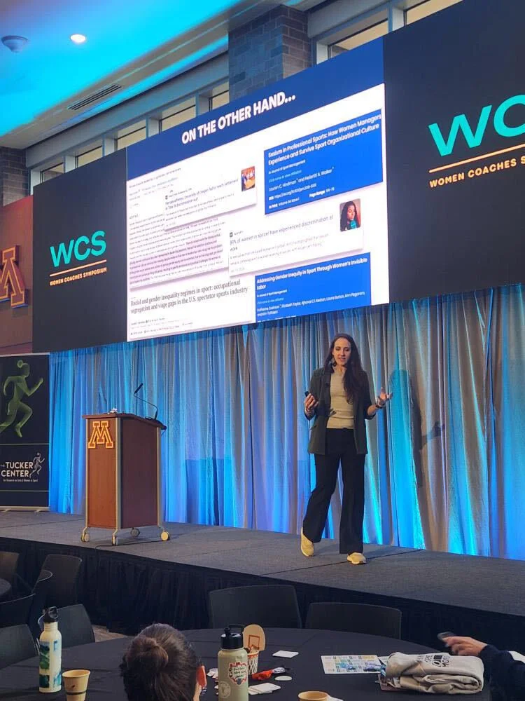 Dr Erin Ayala on stage presenting at the Women's Coaches symposium