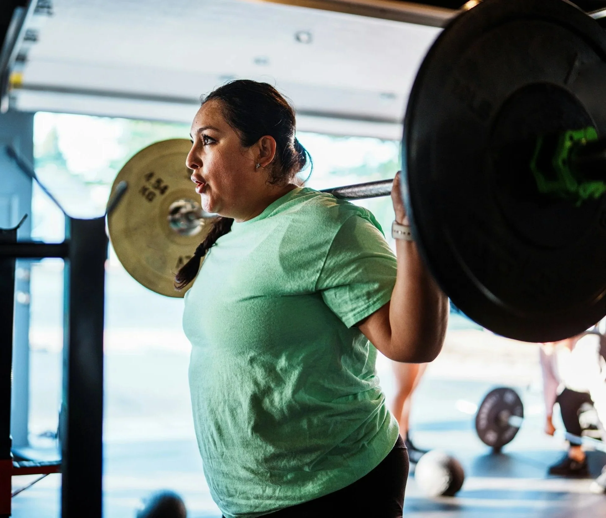 athlete wearing green shirt and lifting weights_skadi collective sports membership