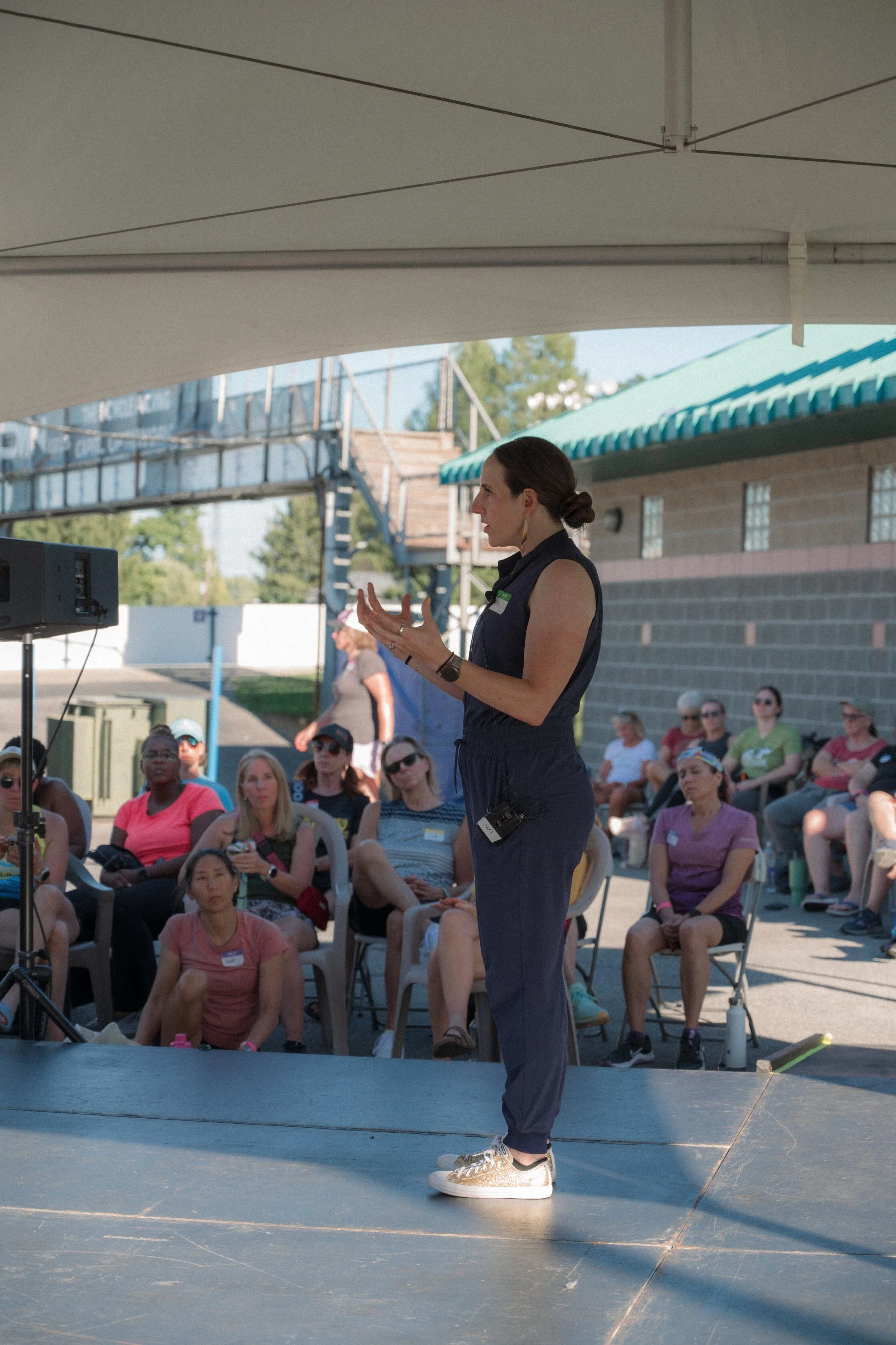 Dr Erin Ayala standing on a stage and speaking to a crowd at an event