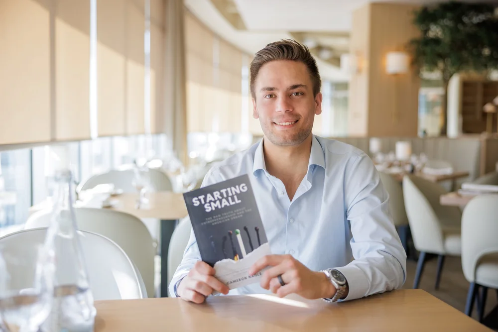 Author Cameron Nagle holding a copy of Starting Small