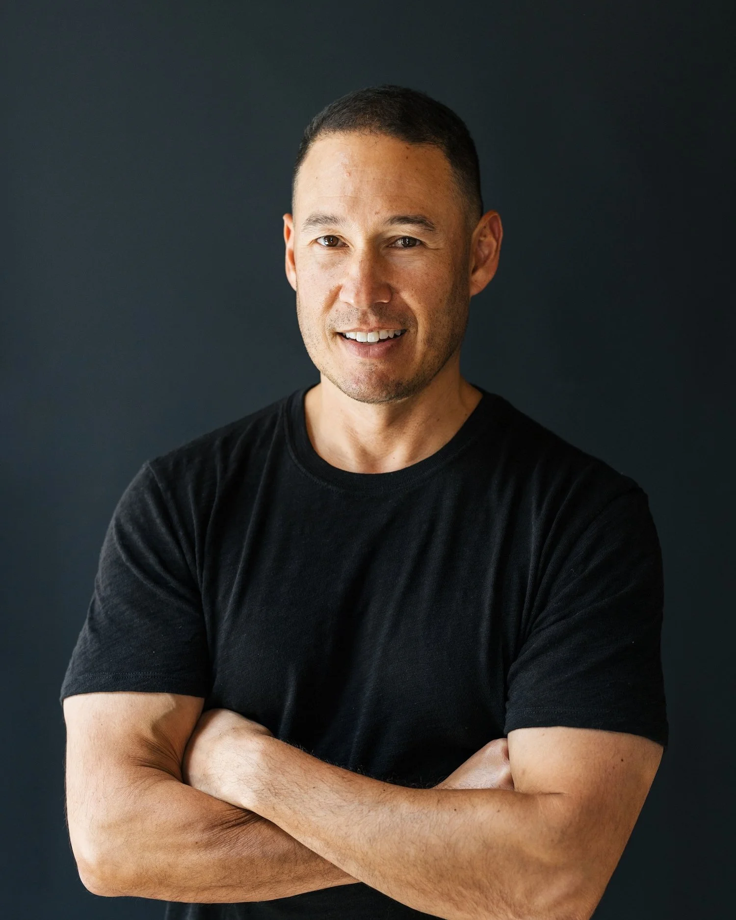 Jared Pobre, founder and CEO of Caldera + Lab, smiling with arms crossed in a black t-shirt