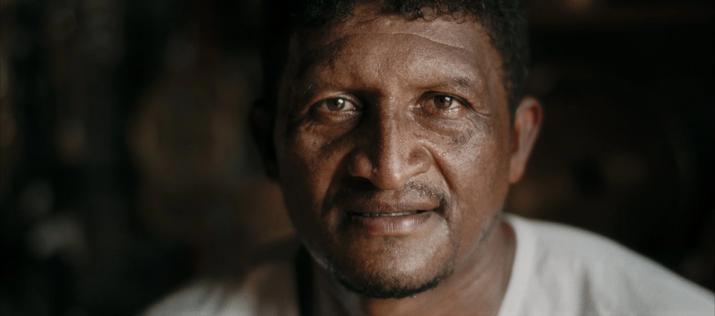 Close-up of a middle-aged Black man with short curly hair, slight facial hair, looking into the camera with a neutral expression.