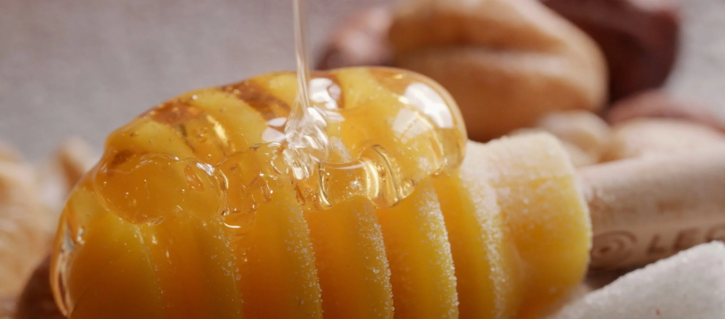 Close-up of honeycomb with honey being poured over it.