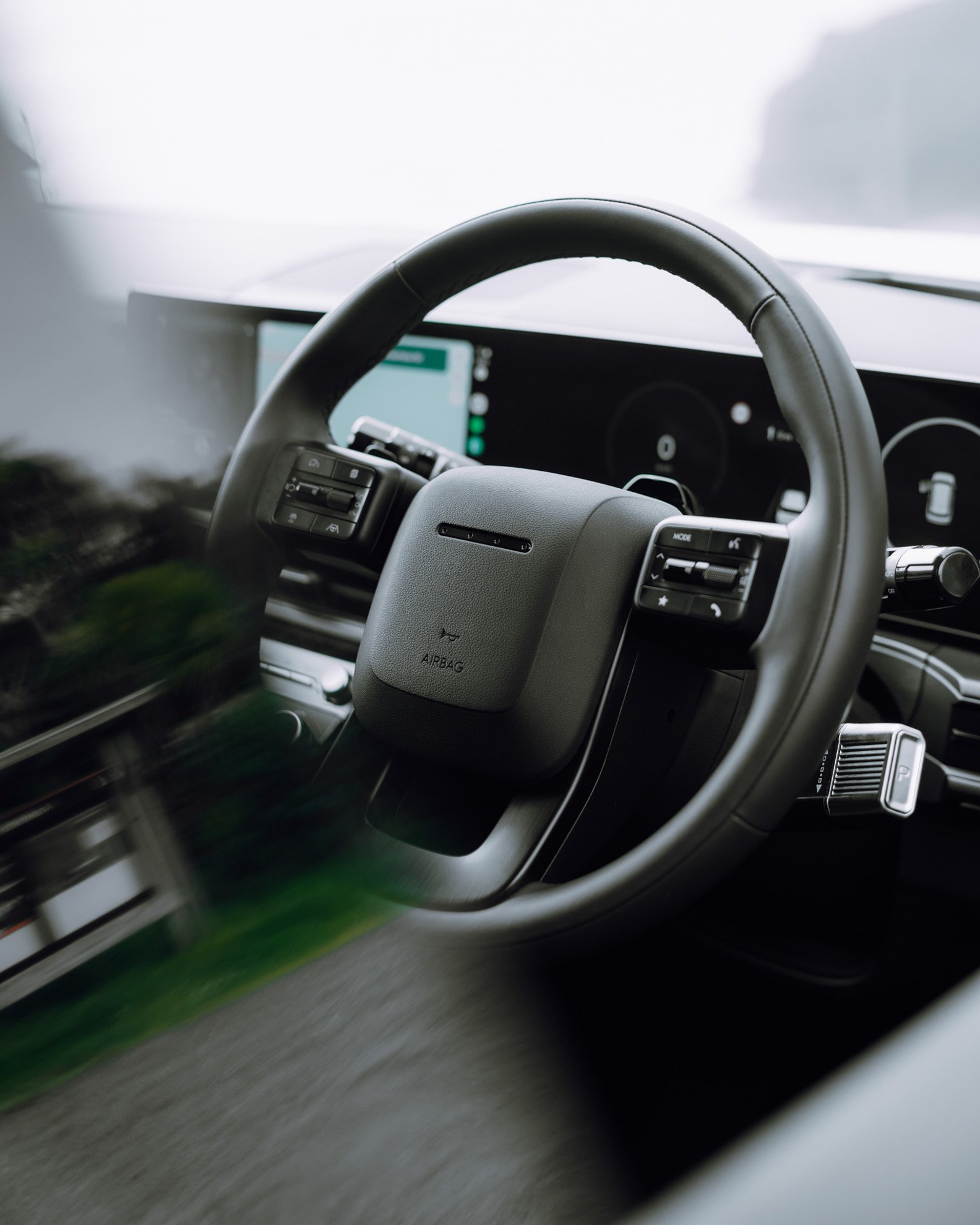 Close-up view of a vehicle's steering wheel and dashboard, with a digital screen in the background.