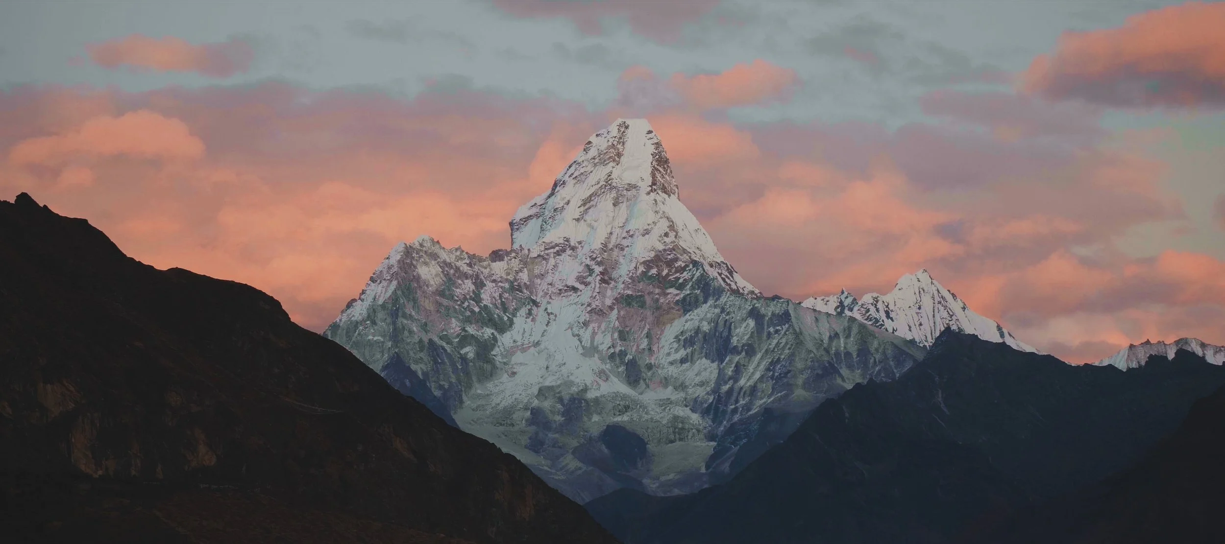 Snow-capped mountain peak at sunset with pink and orange clouds in the sky