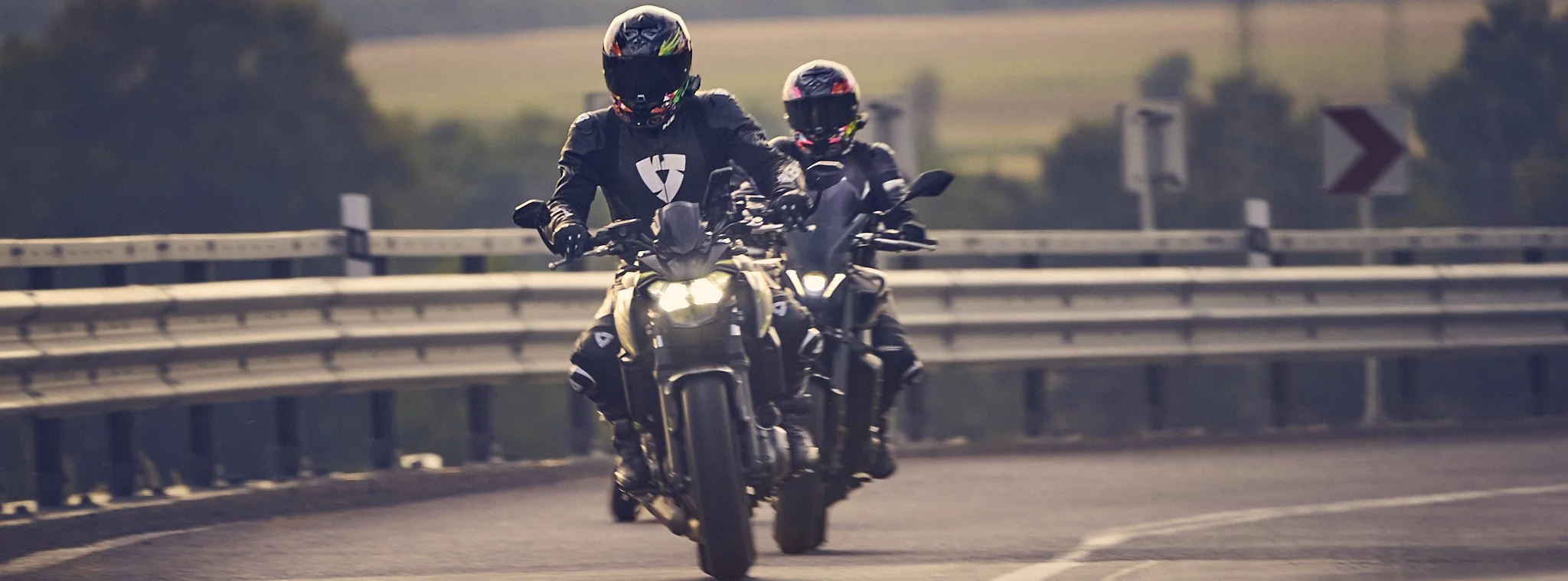 Dva motorkáři zachycení čelně při jízdě v západu slunce