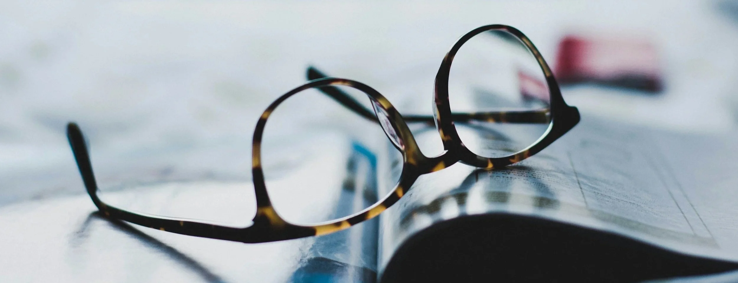 Glasses resting on a notebook or planner, ready to write for your website.