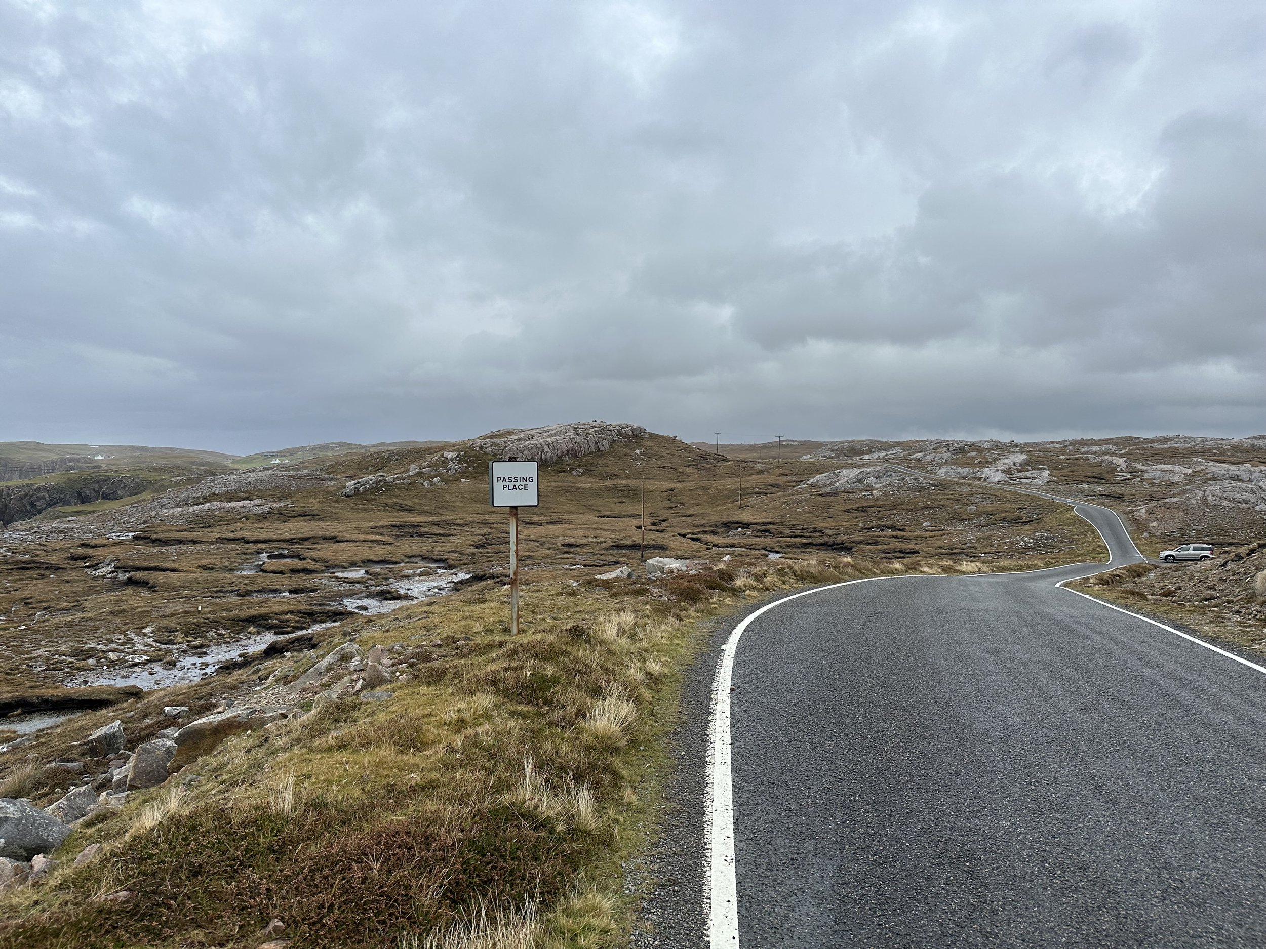 "The sign reads: PASSING PLACE. The single lane road is empty." (p12)