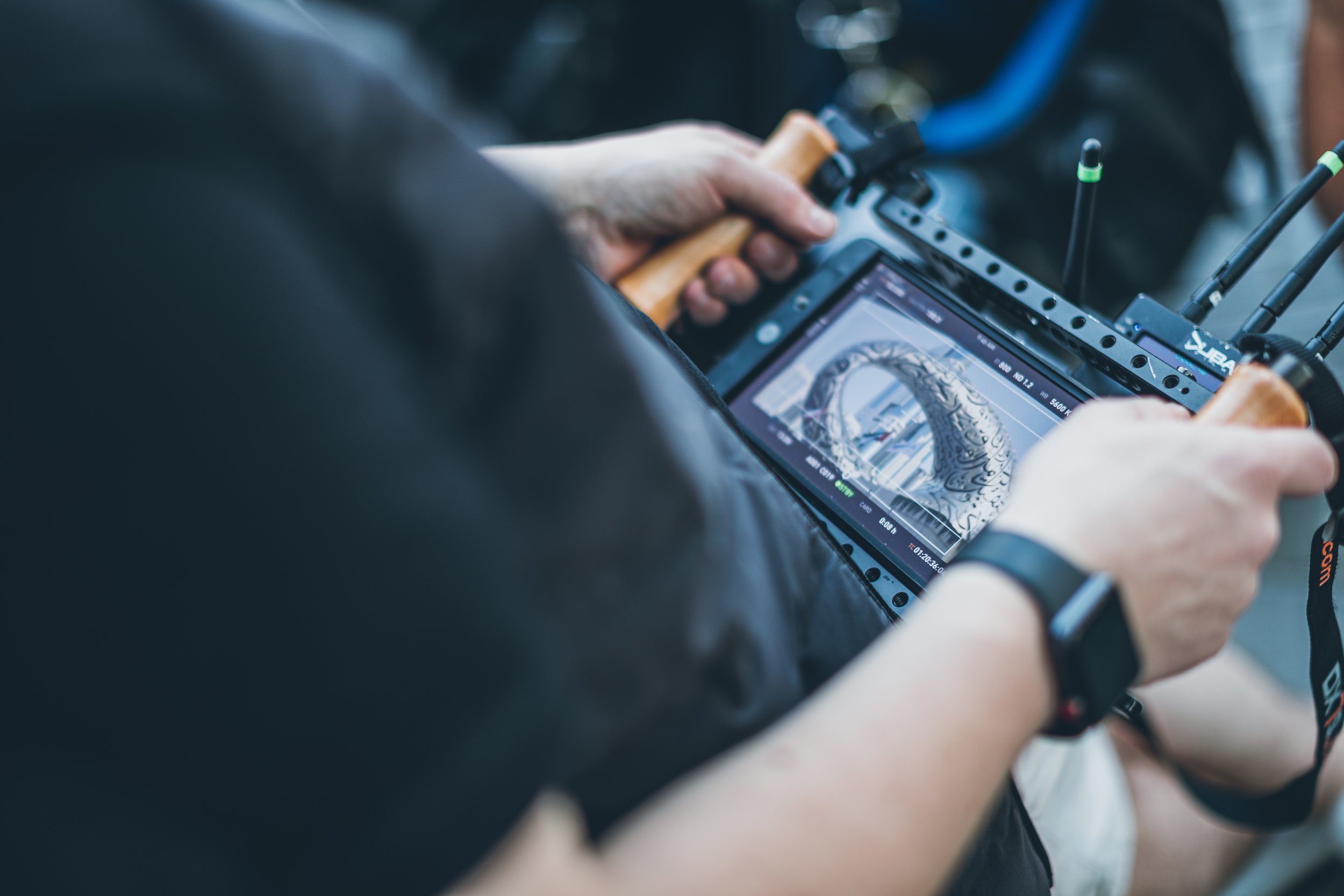 A person holding a drone remote control and a tablet displaying a 3D model of a dragon sculpture.