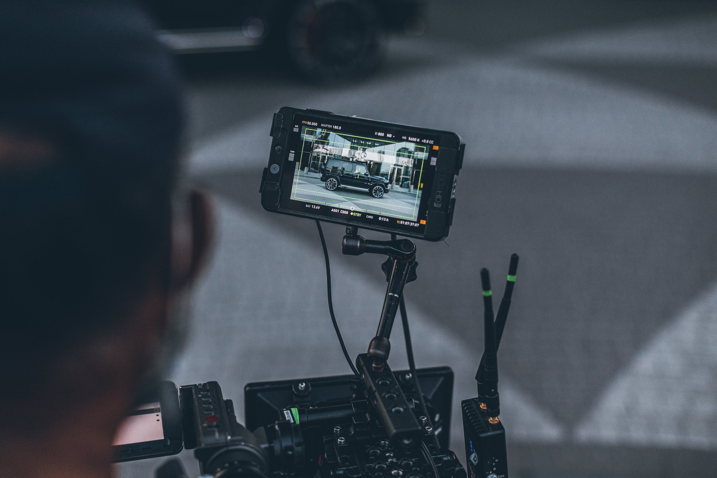 Camera mounted on a rig recording a black SUV parked near a building.