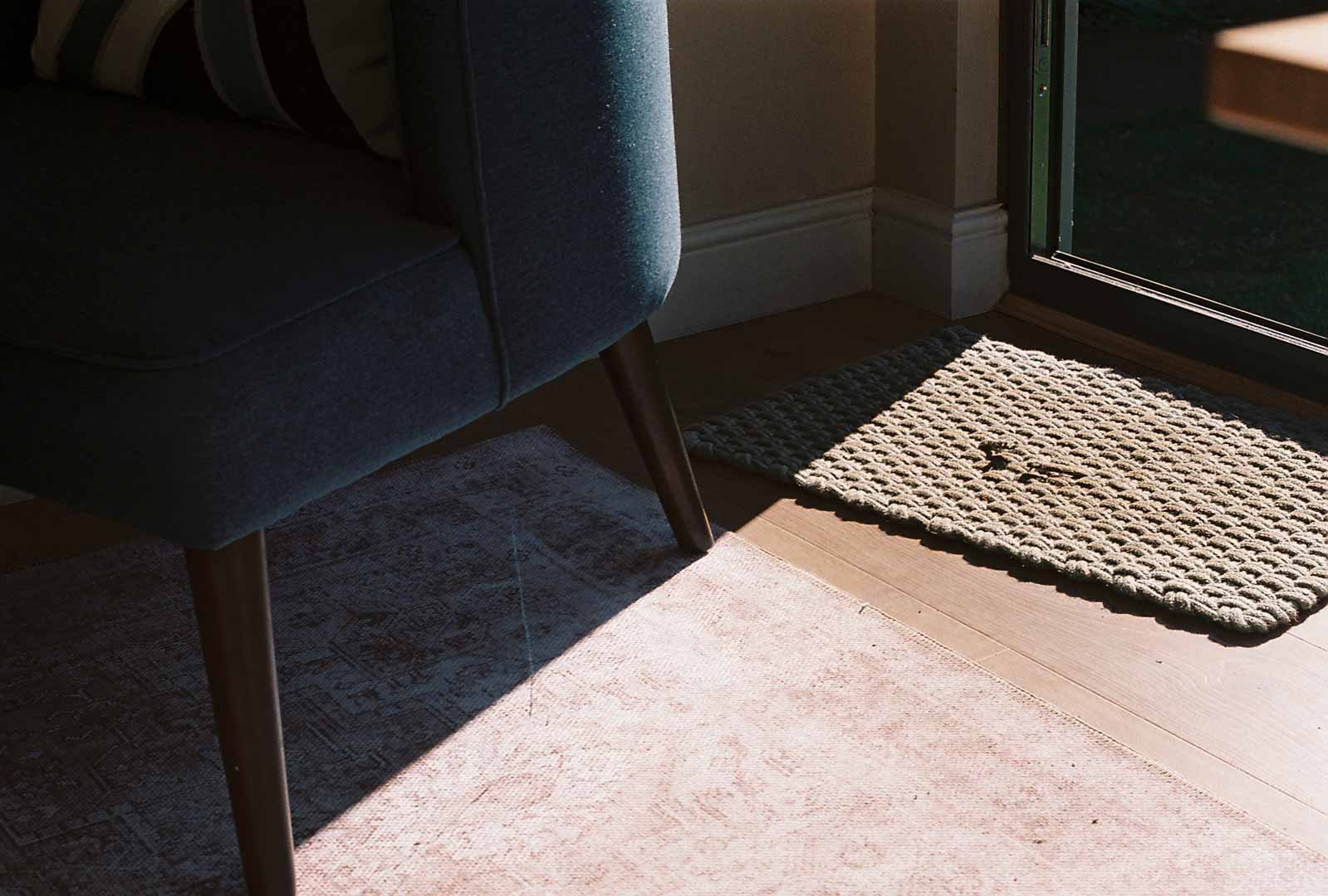 Garden room interior view of a modern room with a chair, rug, and sunlight streaming through a glass door
