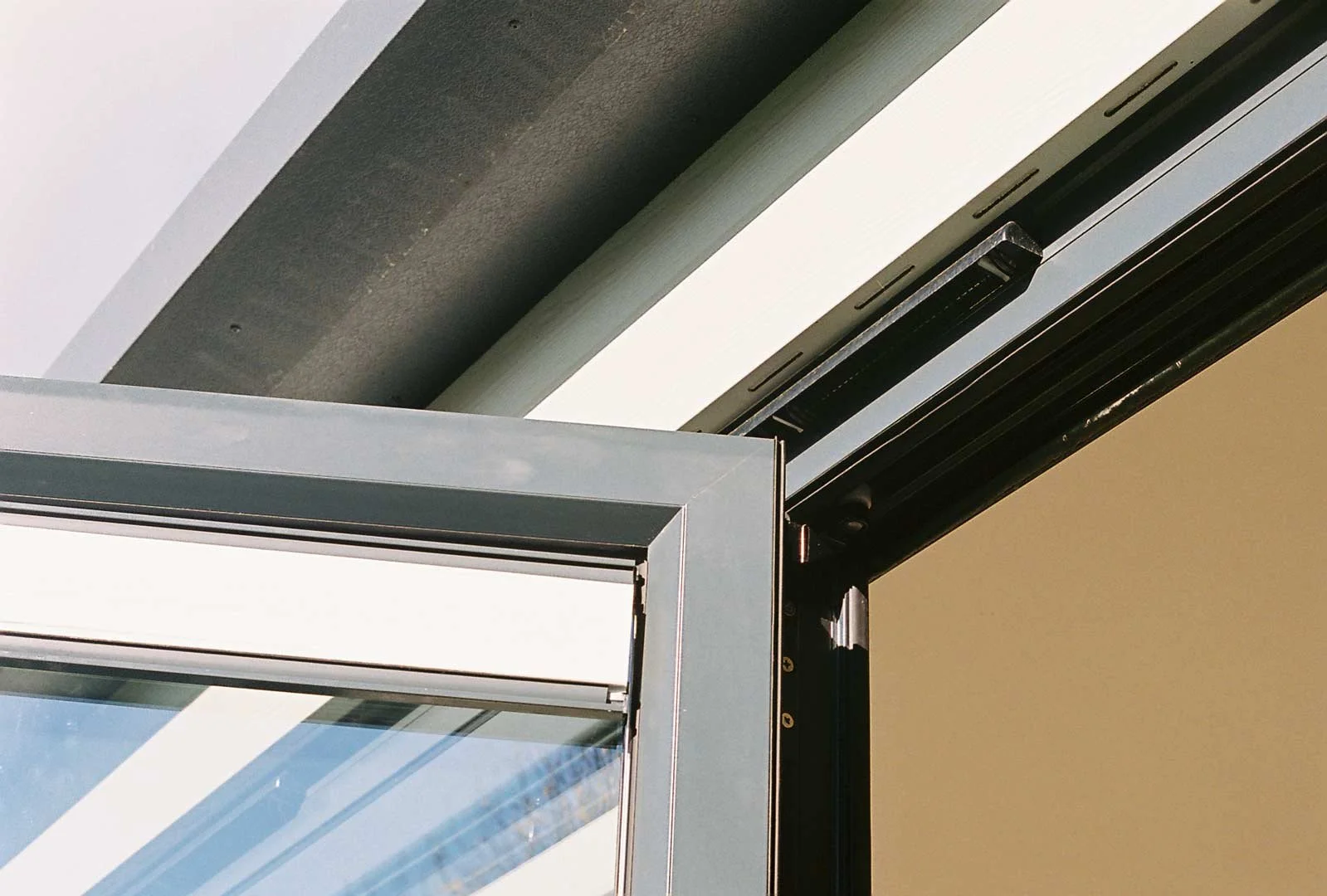 Close-up of an open garden room door frame showing sleek, modern hinge and glazing detail