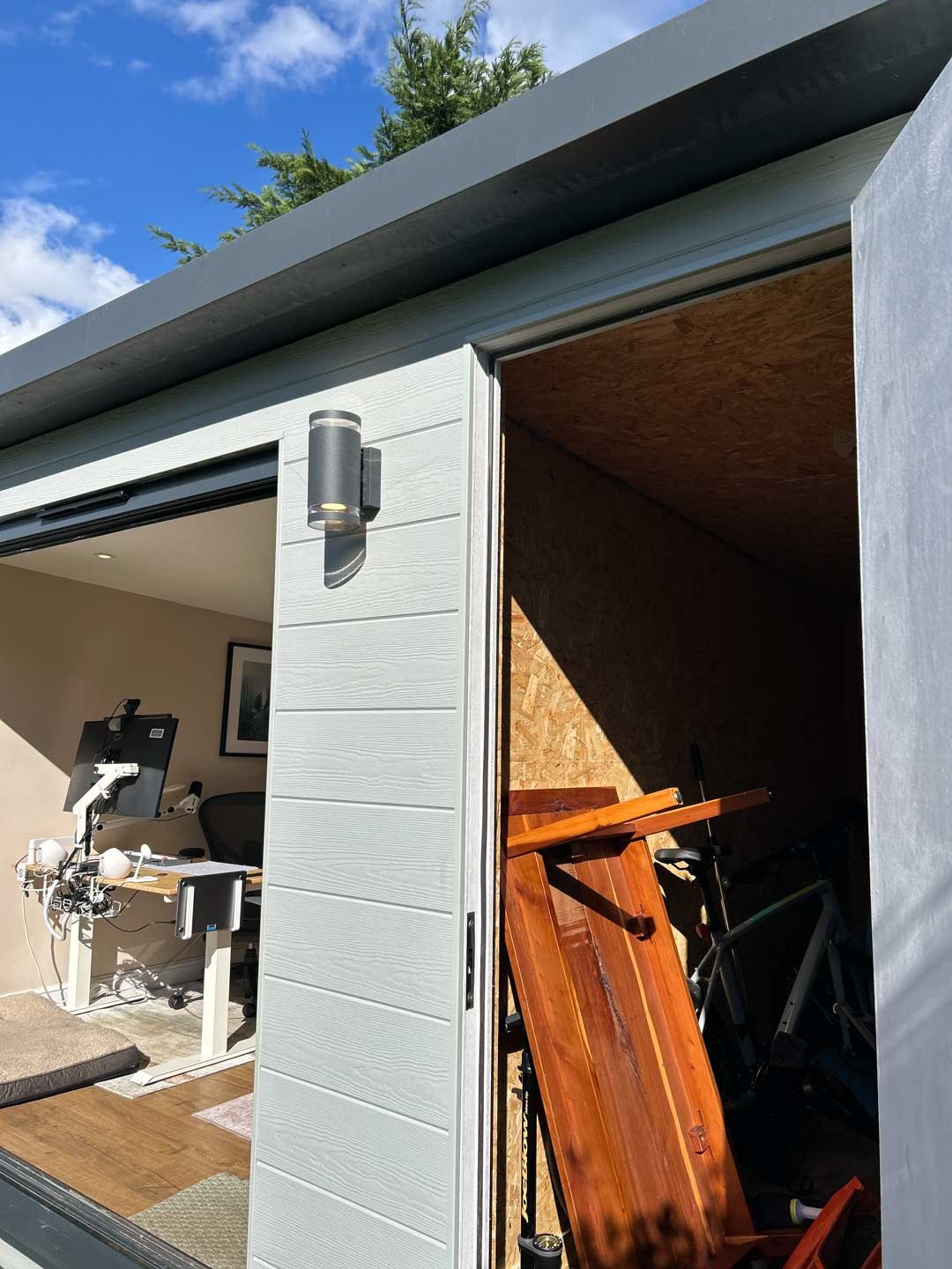Garden room with open side door, showing interior workspace and equipment storage area