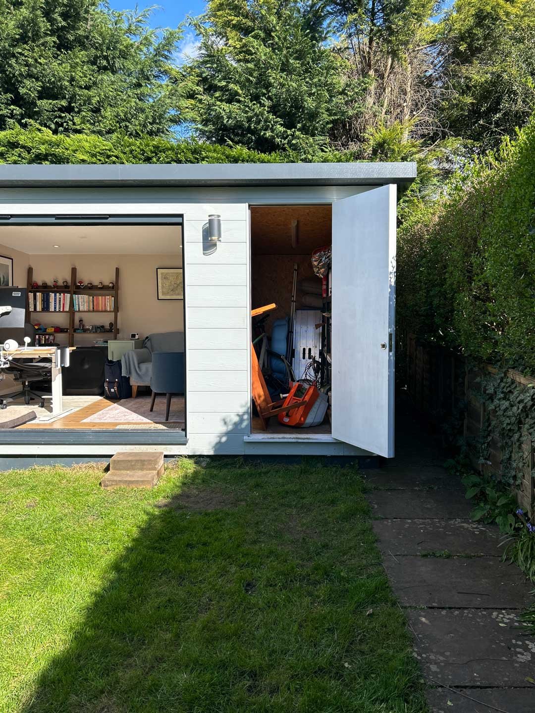 Bespoke garden room with doors open, revealing a modern workspace and storage area inside
