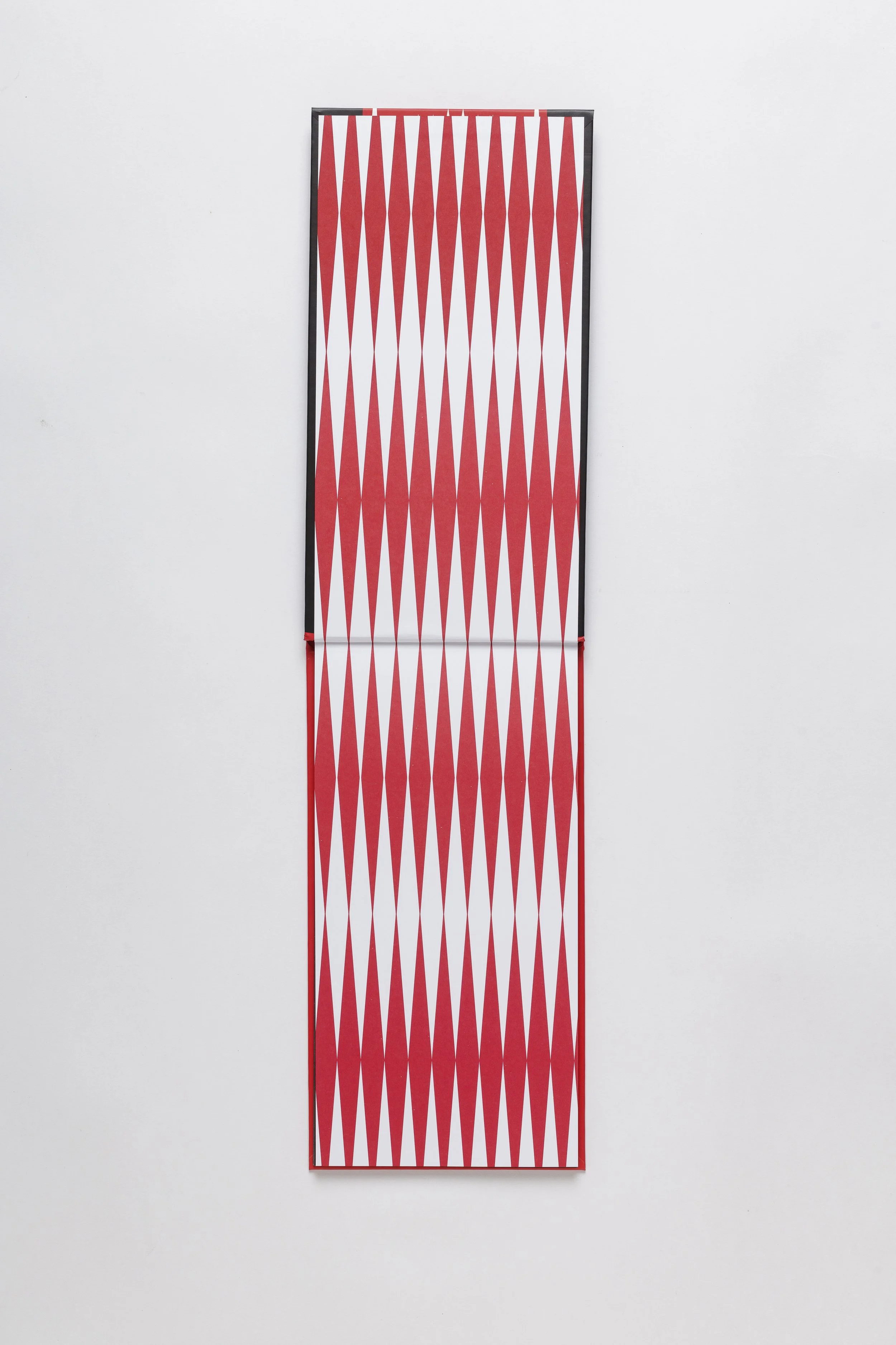 Fully opened picturebook showing repeating red and white die-cut pattern across spreads