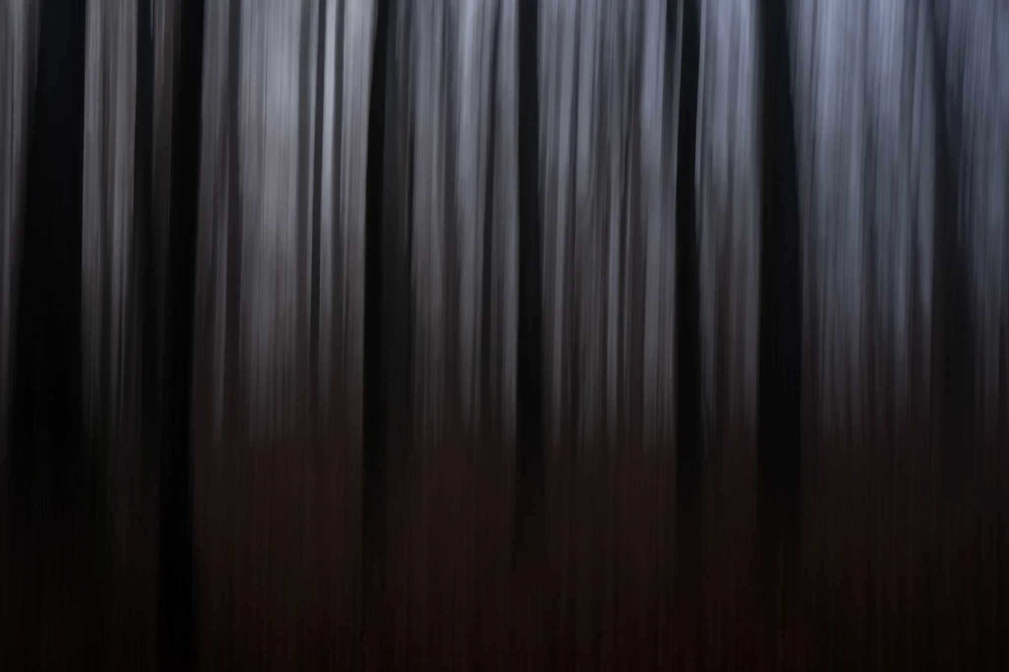 Blurred image of vertical bars or slats with a dark, reflective surface.