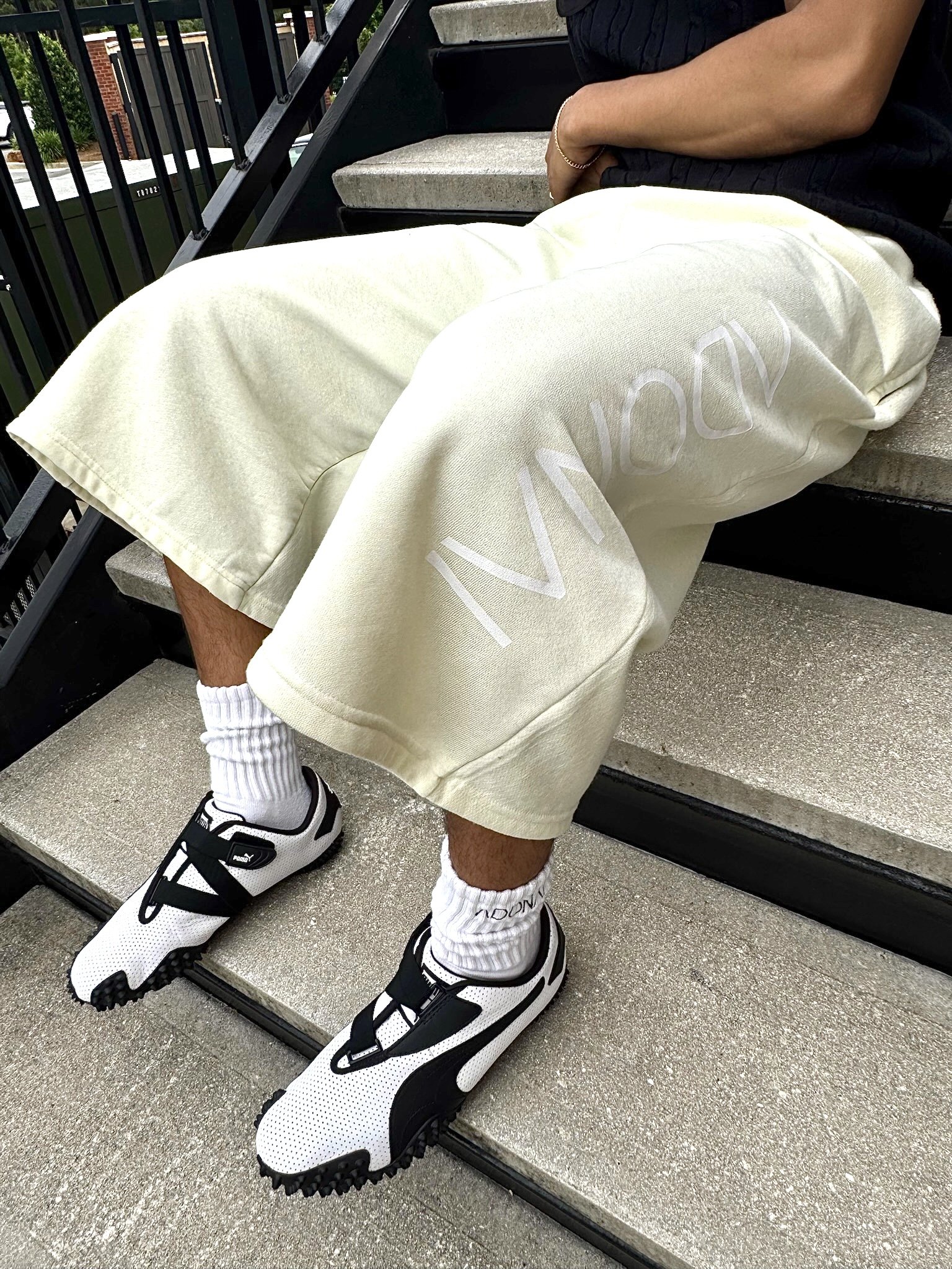 Model wearing Luxury Capri or 3/4 or Long shorts. Yellow oversized shorts, heavyweight cotton, fleece, sweat shorts, fashionable trending. oversized logo, street style