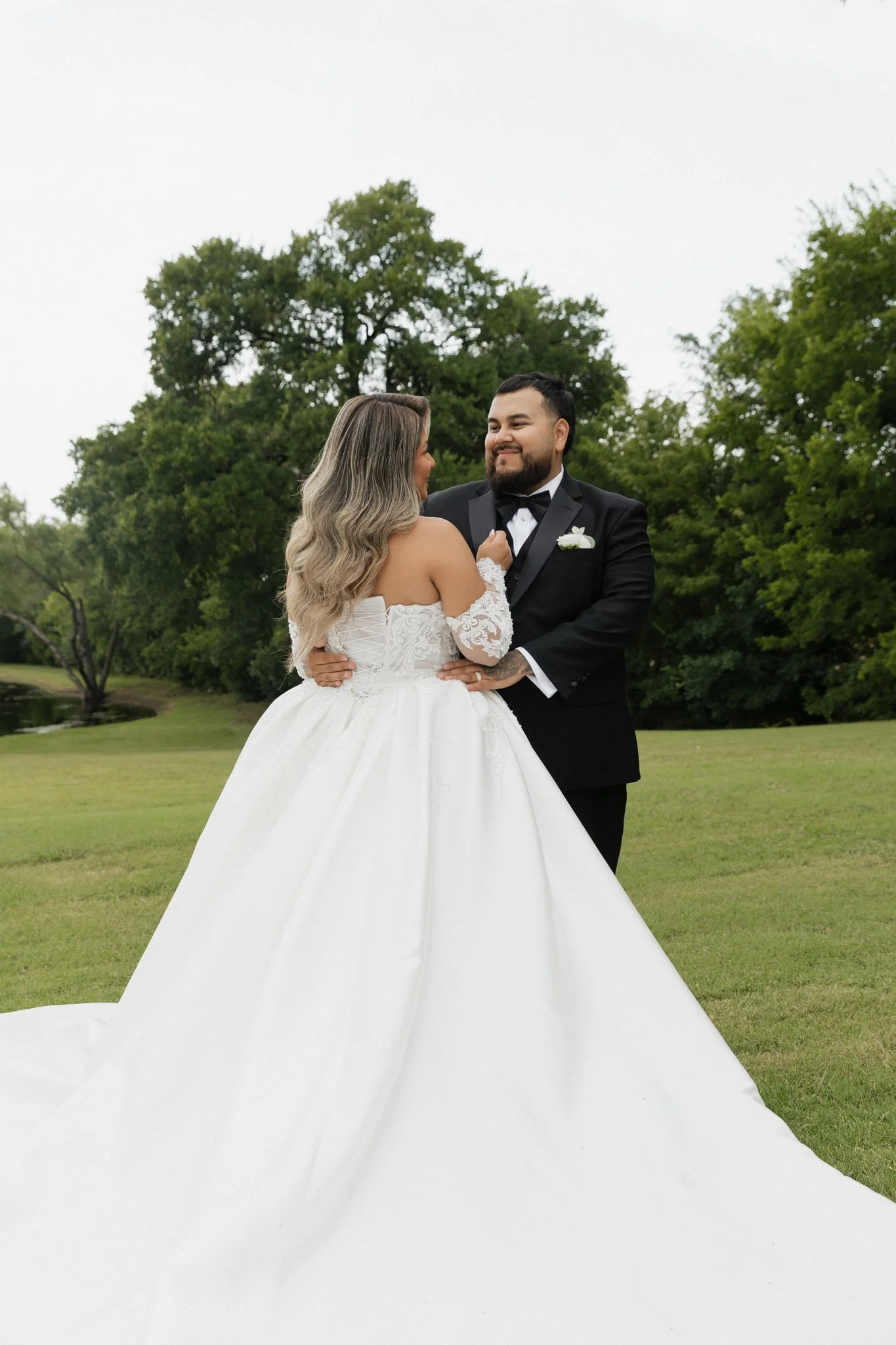 Bride and groom sharing a moment outdoors, with trees and greenery in the background.