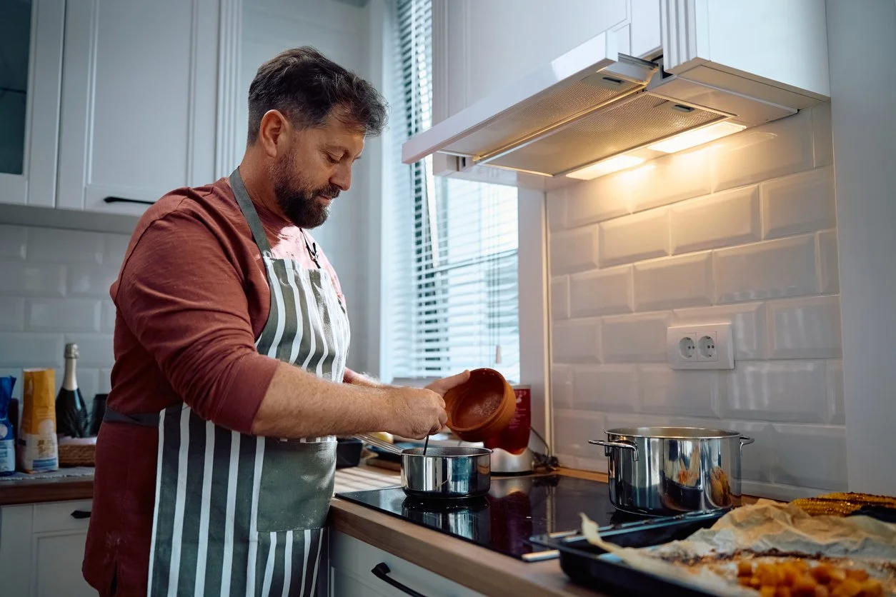 man in striped apron stirring pot on the stove
