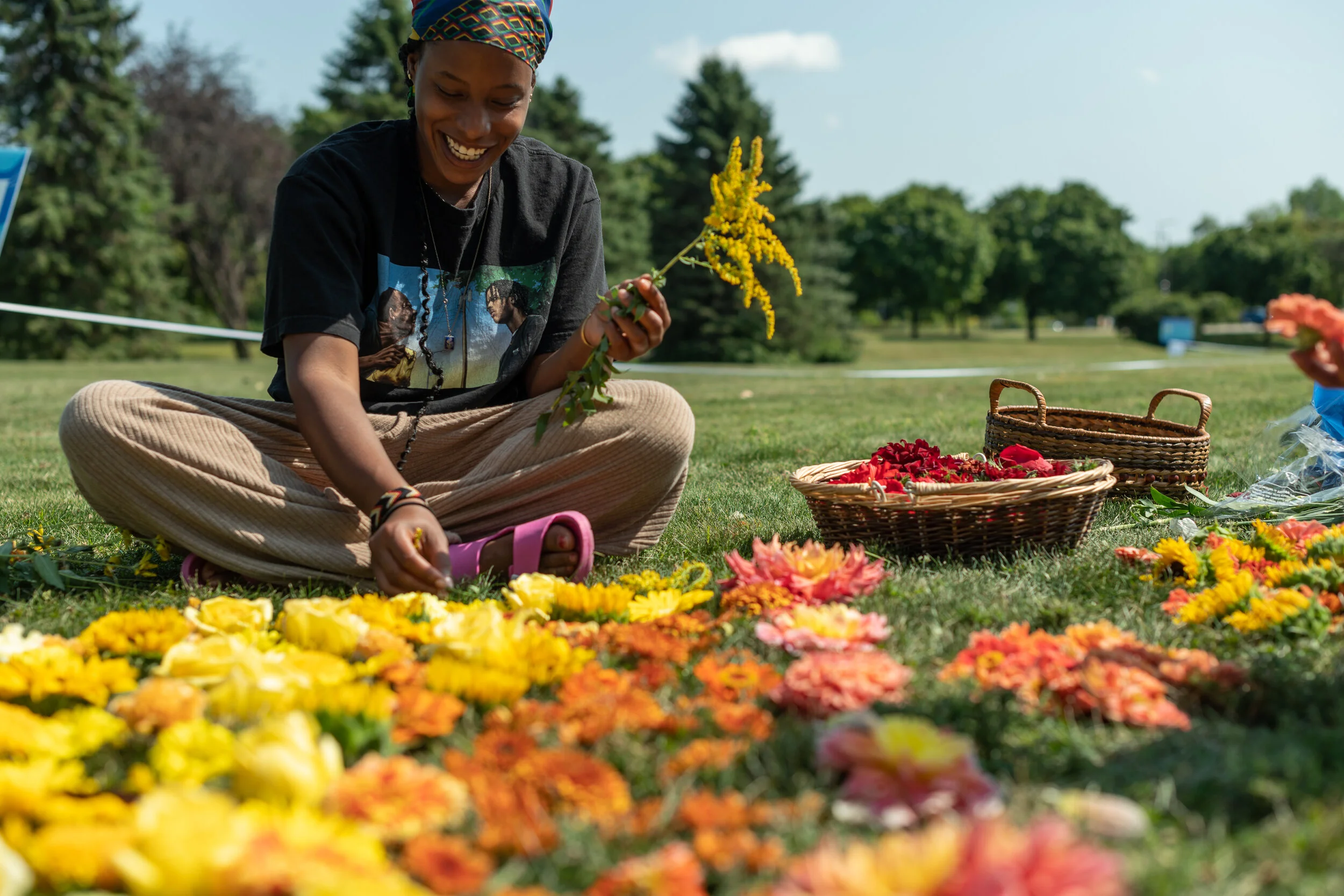 [An artist smiles while laying flowers at one of seven art installations along the path of Phalen Creek. Photo credit: Caroline Yang.]