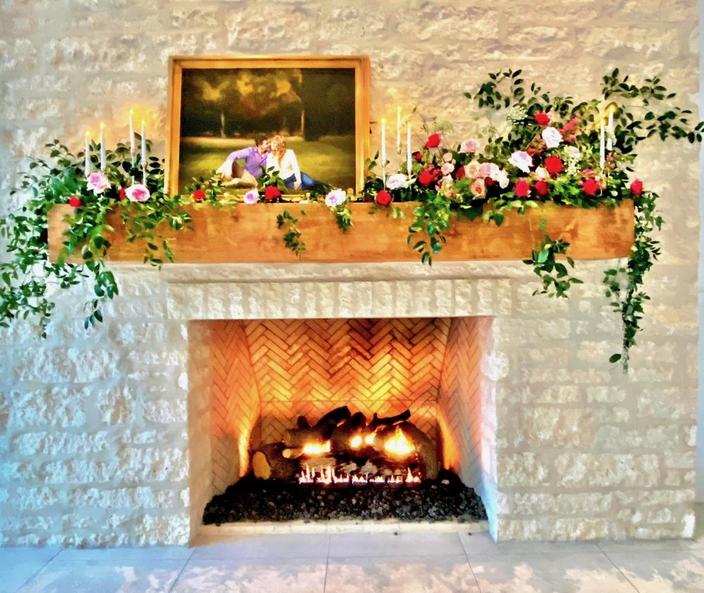 large oil painted engagement portrait above fireplace and accented by floral at wedding