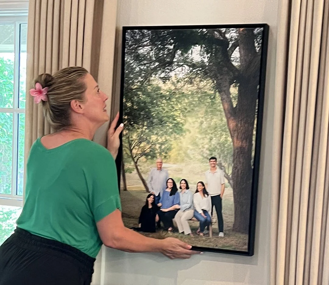 Heidi Knight installing a large commissioned family portrait artwork in a client's home in Central Texas.